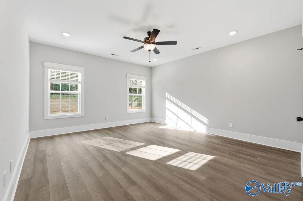 Bright secondary bedroom with gray walls, hardwood floors, large windows, and ceiling fan in Davidson Homes The Rockford, Hartselle, Alabama