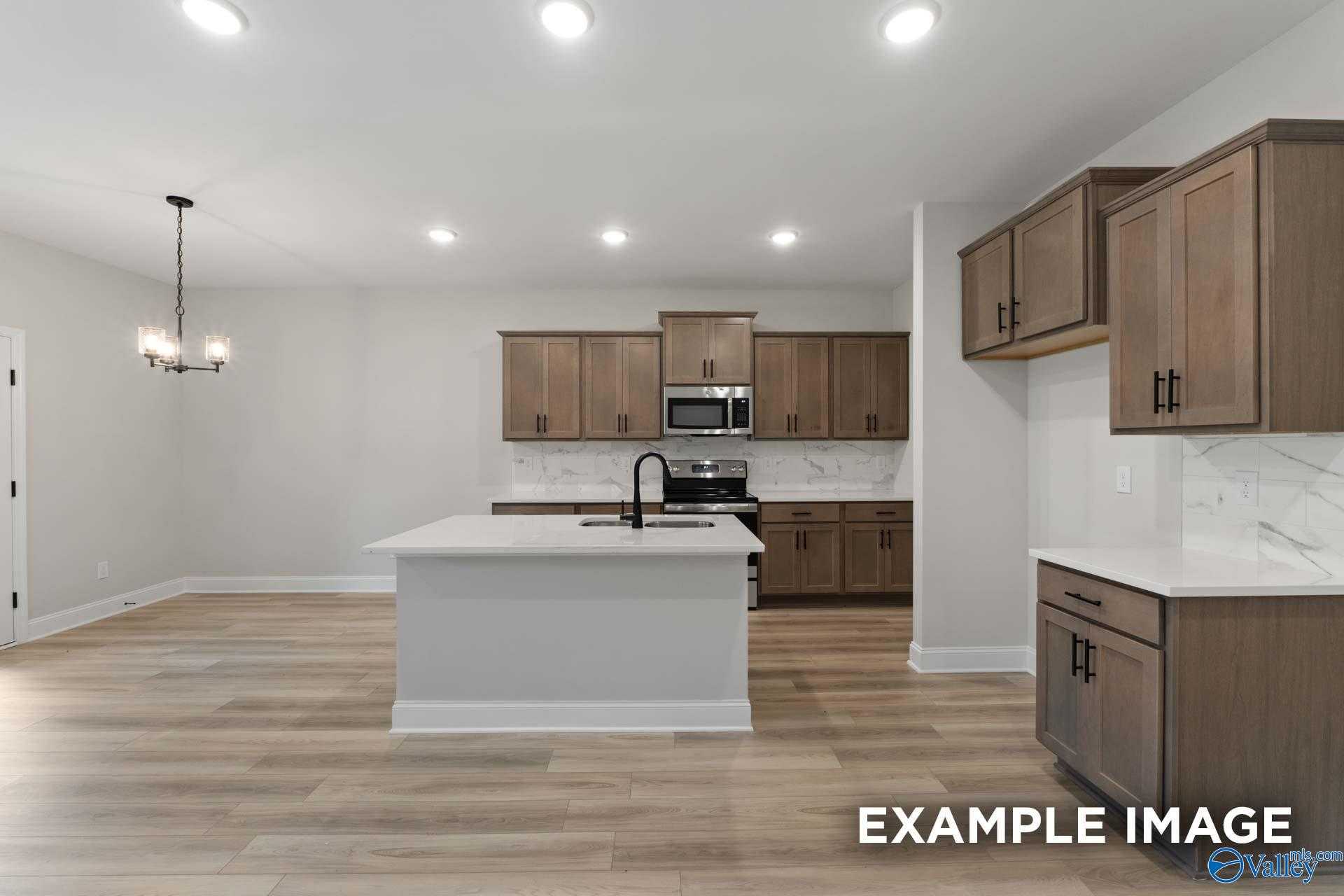 Modern open-concept kitchen with white quartz island, espresso shaker cabinets, stainless appliances in The Camden D home, Huntsville AL