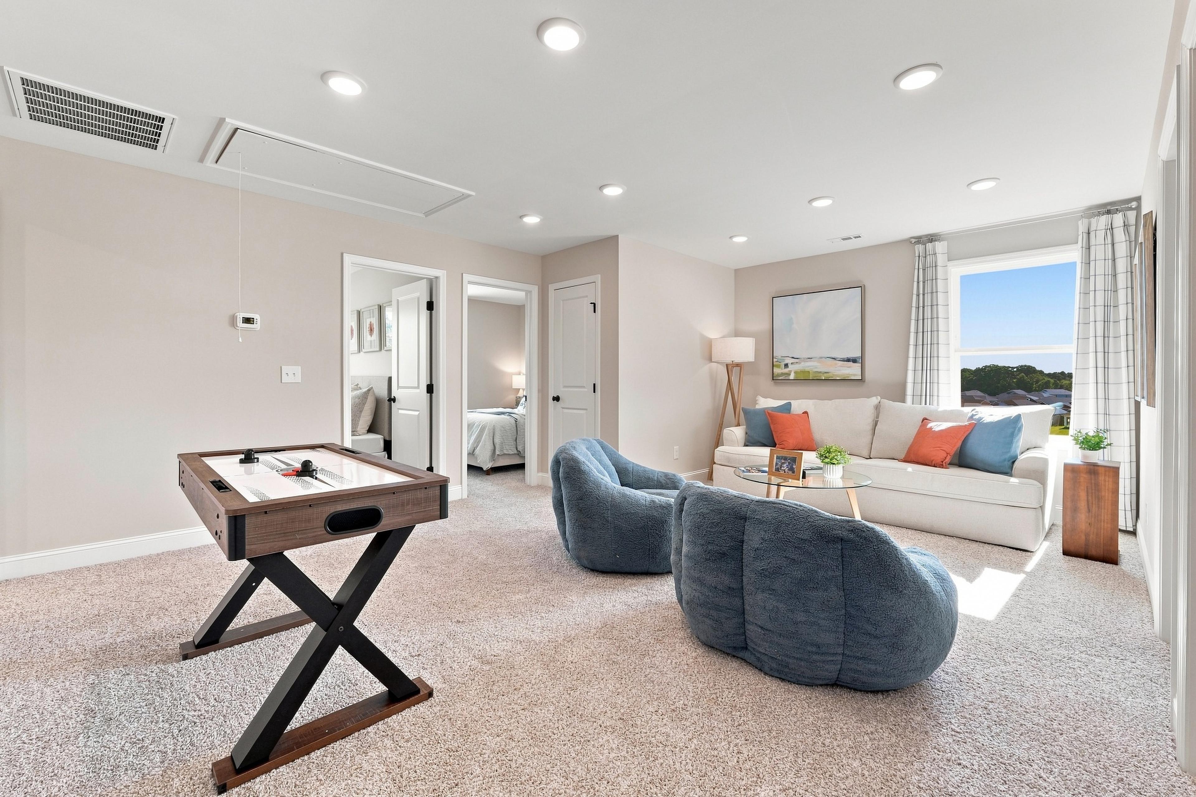 Spacious game room and living area at Bailey Park in Fayetteville, TN by Davidson Homes with air hockey table and cozy seating