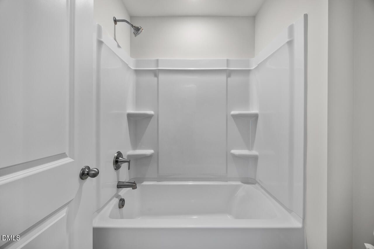 Modern white bathtub and shower combo in The Mitchell Interior floor plan at Forestville Yard Townhomes in Knightdale, NC.