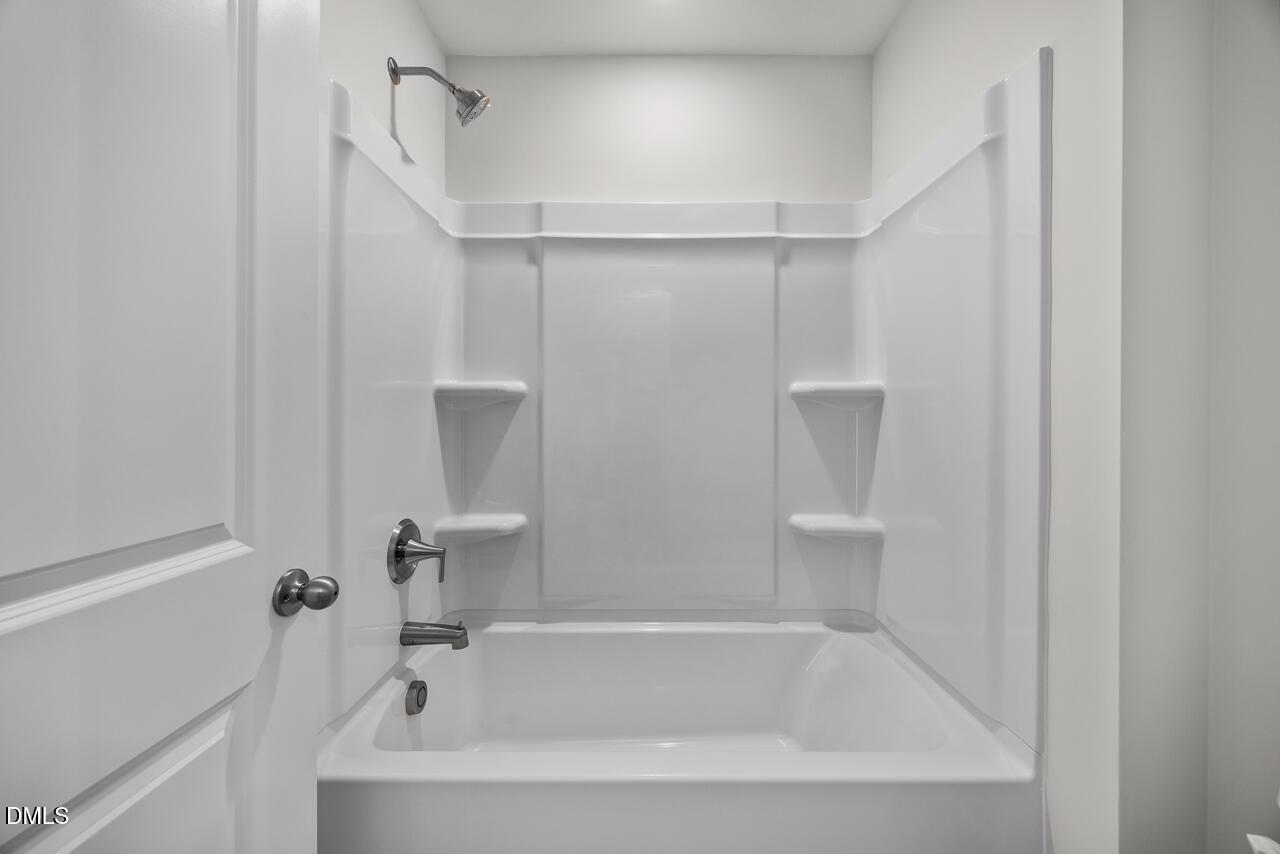 Modern white bathtub and shower combo in The Mitchell Interior floor plan at Forestville Yard Townhomes in Knightdale, NC.