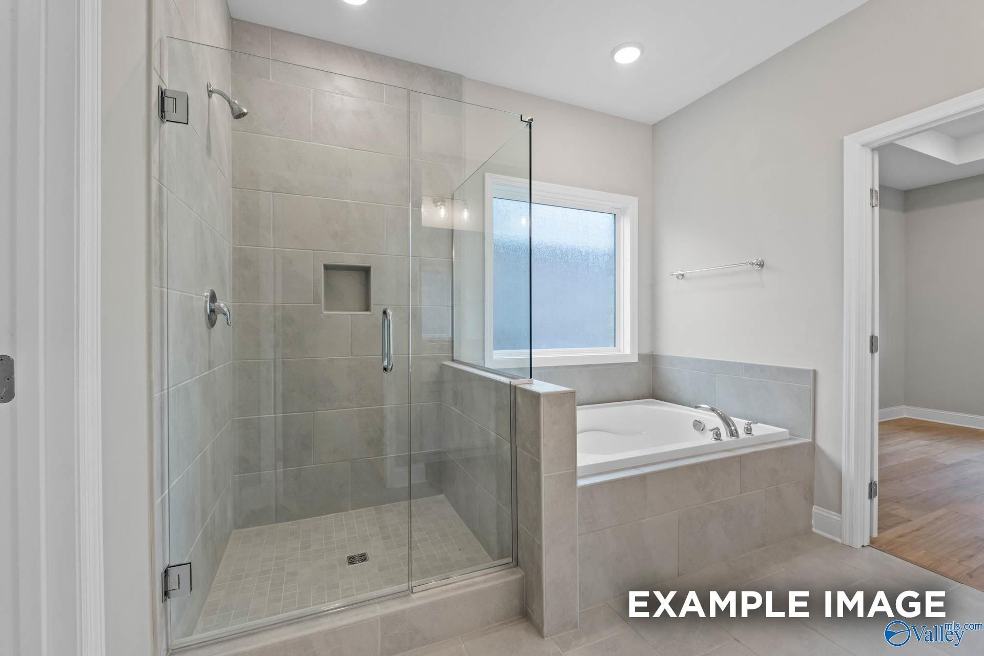 Modern master bathroom featuring frameless glass shower, soaking tub, and frosted window in Davidson Homes The Montgomery, Meridianville, Alabama