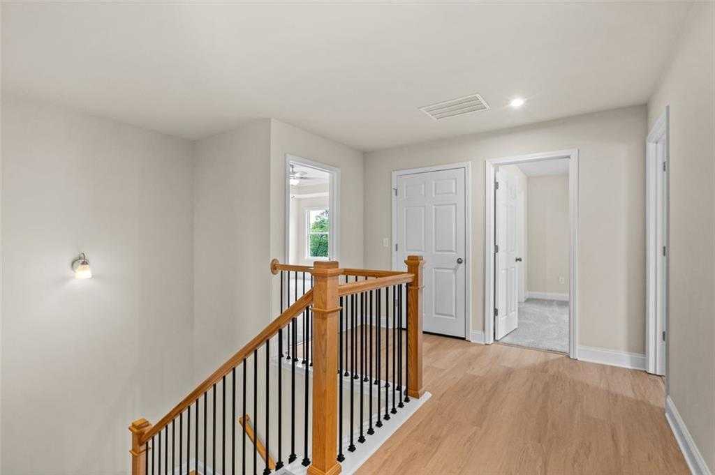 Elegant oak staircase with black balusters leading to beige upstairs hallway and white doors in Davidson Homes The Hickory B at Wehunt Meadows, Hoschton
