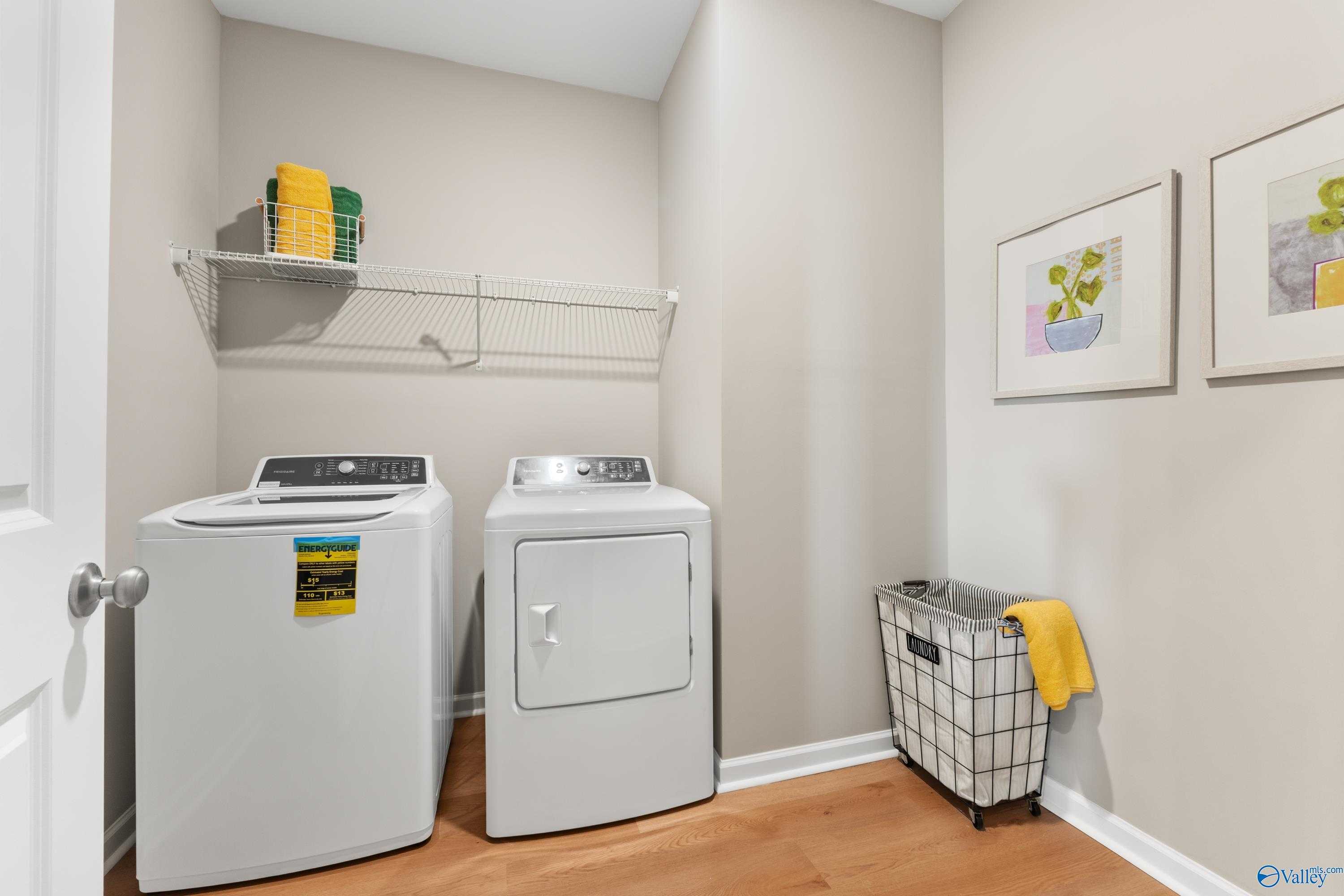 Modern laundry room with front-load washer, dryer, storage shelves, and basket in Davidson Homes The Sanctuary, Athens, AL