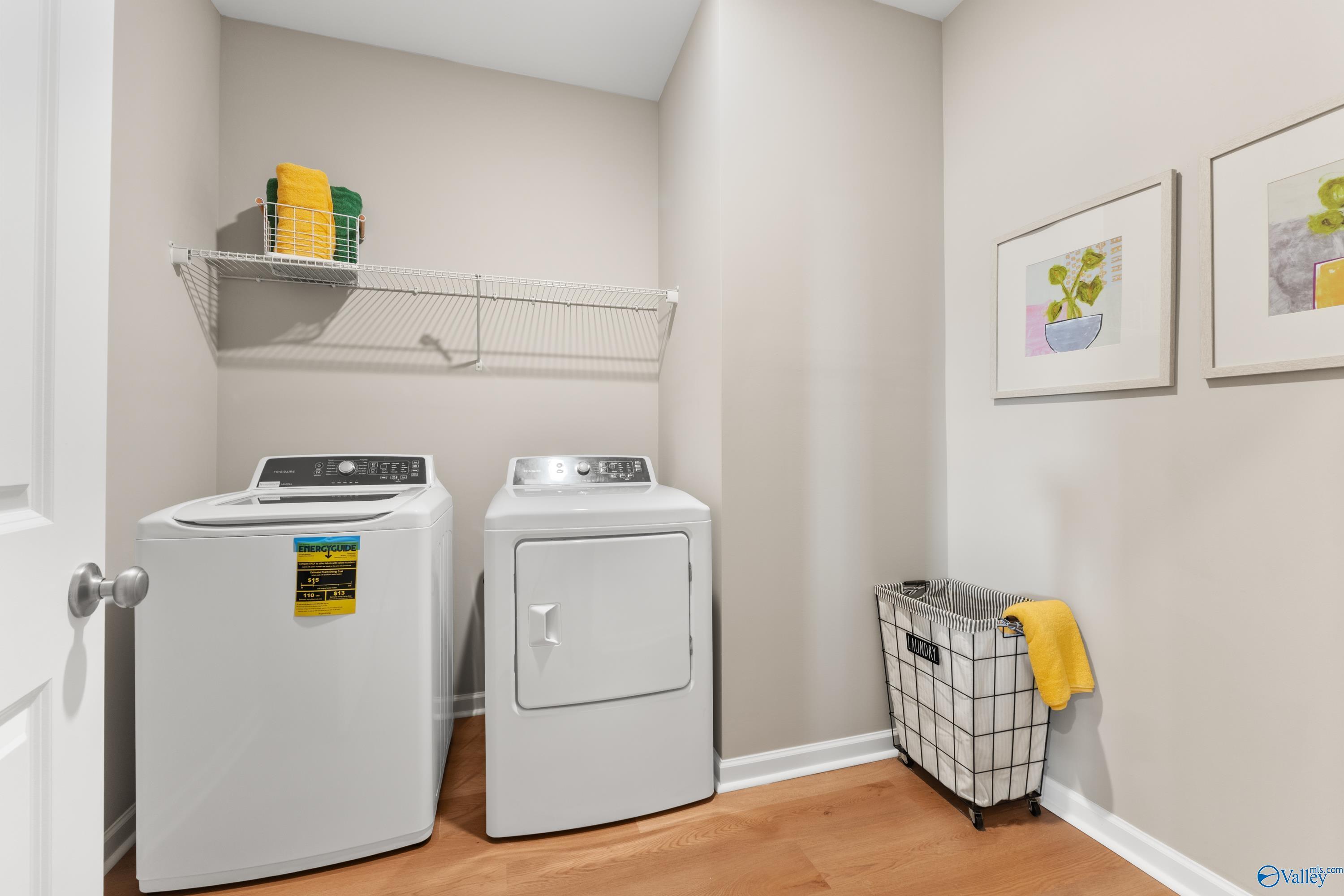 Modern laundry room with front-load washer, dryer, storage shelves, and basket in Davidson Homes The Sanctuary, Athens, AL