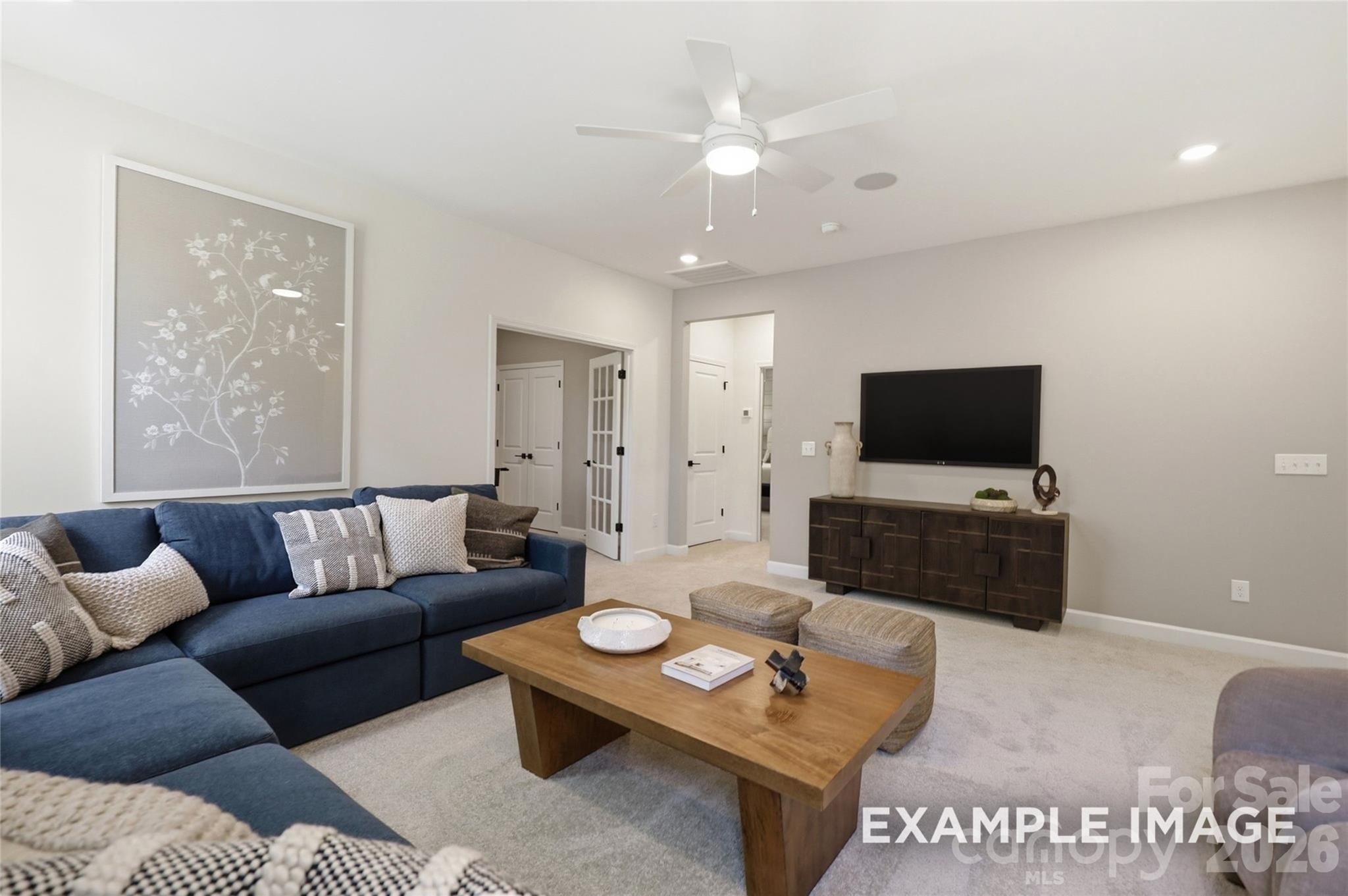Bright family room with navy sectional, wood coffee table, and mounted TV in Davidson Homes The Aspen B, Windgate, Mooresville NC