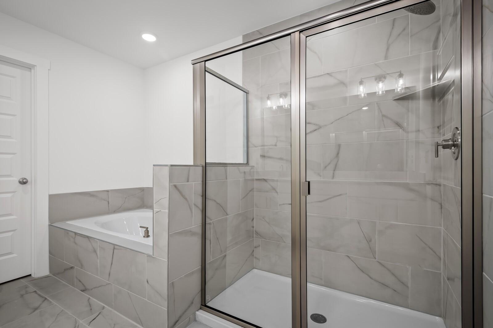 Modern master bathroom with tiled walk-in shower and soaking tub in The Logan C floor plan at Calista Farms, White House, TN.