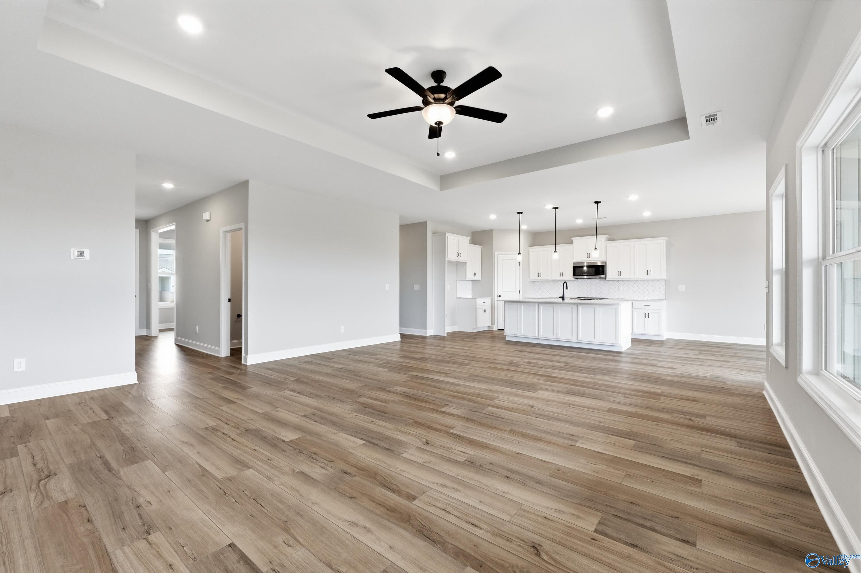 Open-concept living and kitchen with white island, hardwood floors, ceiling fan in Davidson Homes The Rockford C, Athens AL