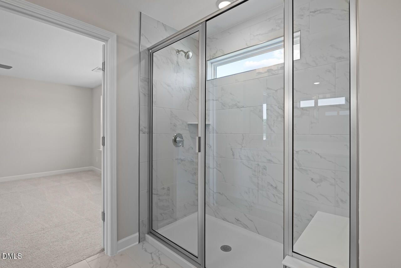 Walk-in glass shower with marble-style tile in The Chestnut floor plan at Wendell Ridge in Wendell, North Carolina.