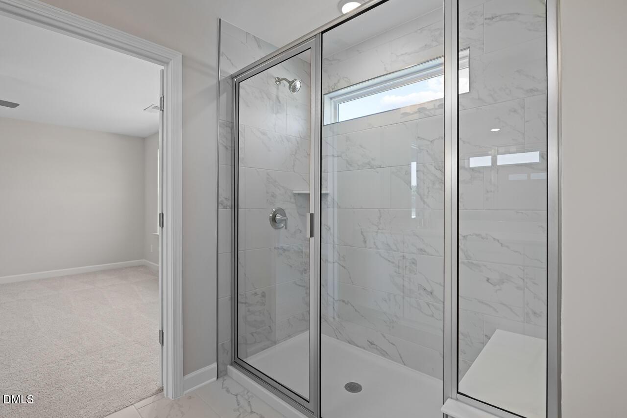 Walk-in glass shower with marble-style tile in The Chestnut floor plan at Wendell Ridge in Wendell, North Carolina.