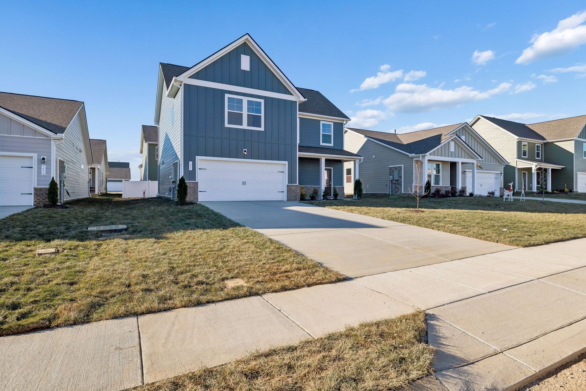 Blue two-story Gordon B home with white trim, two-car garage, driveway, and manicured lawn in Sage Farms, White House, TN