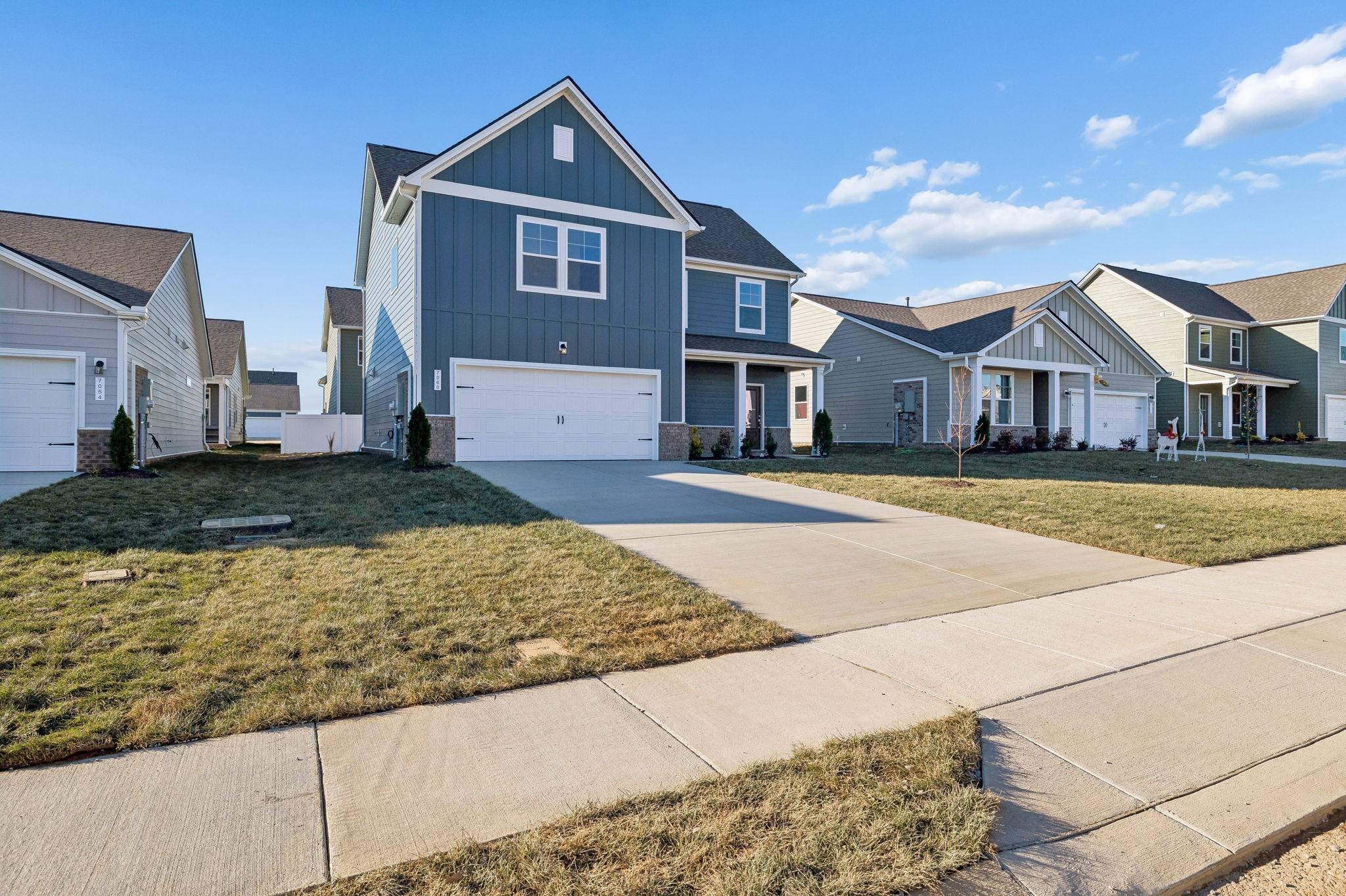 Blue two-story Gordon B home with white trim, two-car garage, driveway, and manicured lawn in Sage Farms, White House, TN