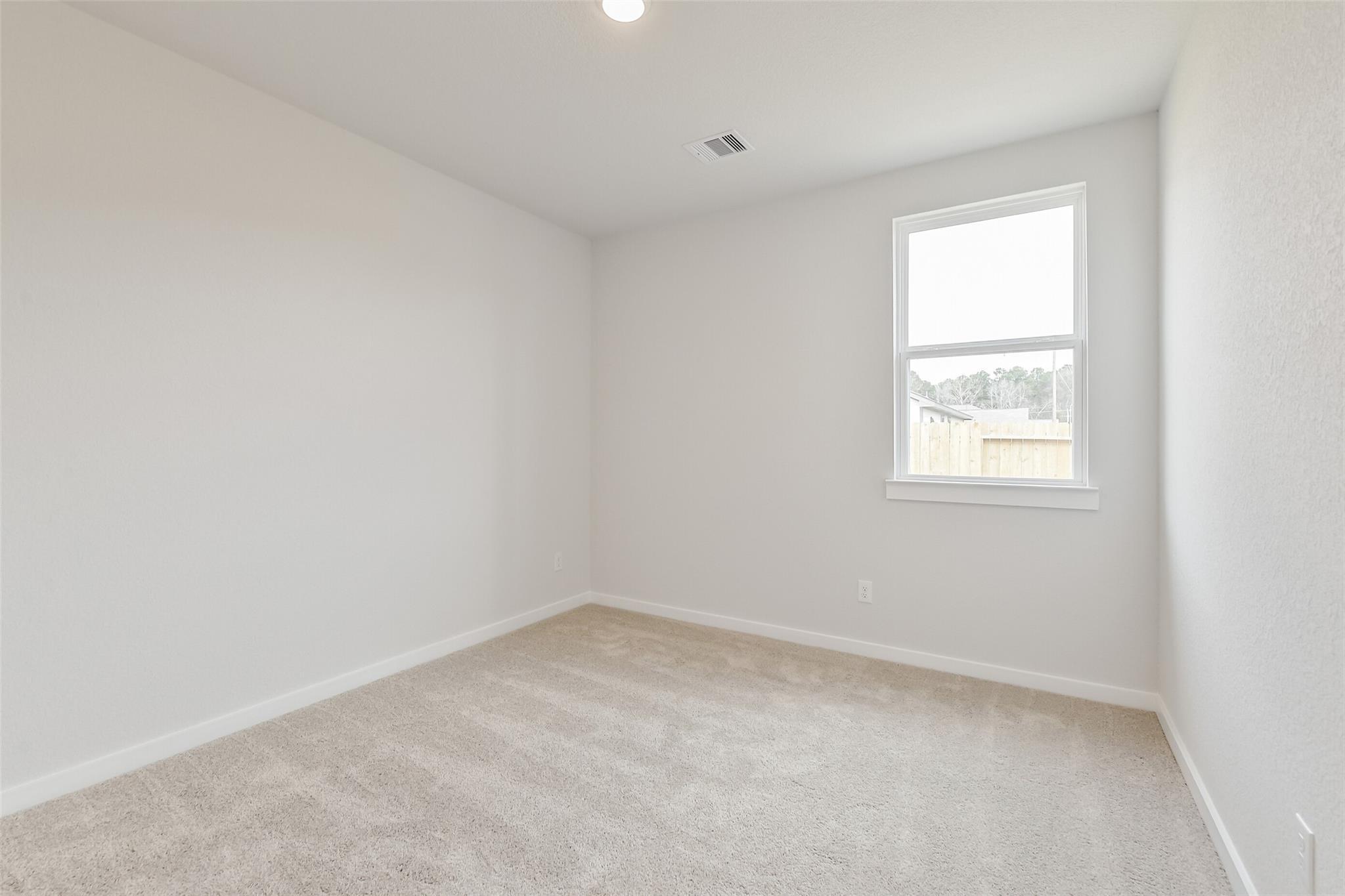 Bright secondary bedroom with beige carpet, white walls, and large window in Davidson Homes The Frio G, Cleveland, Texas