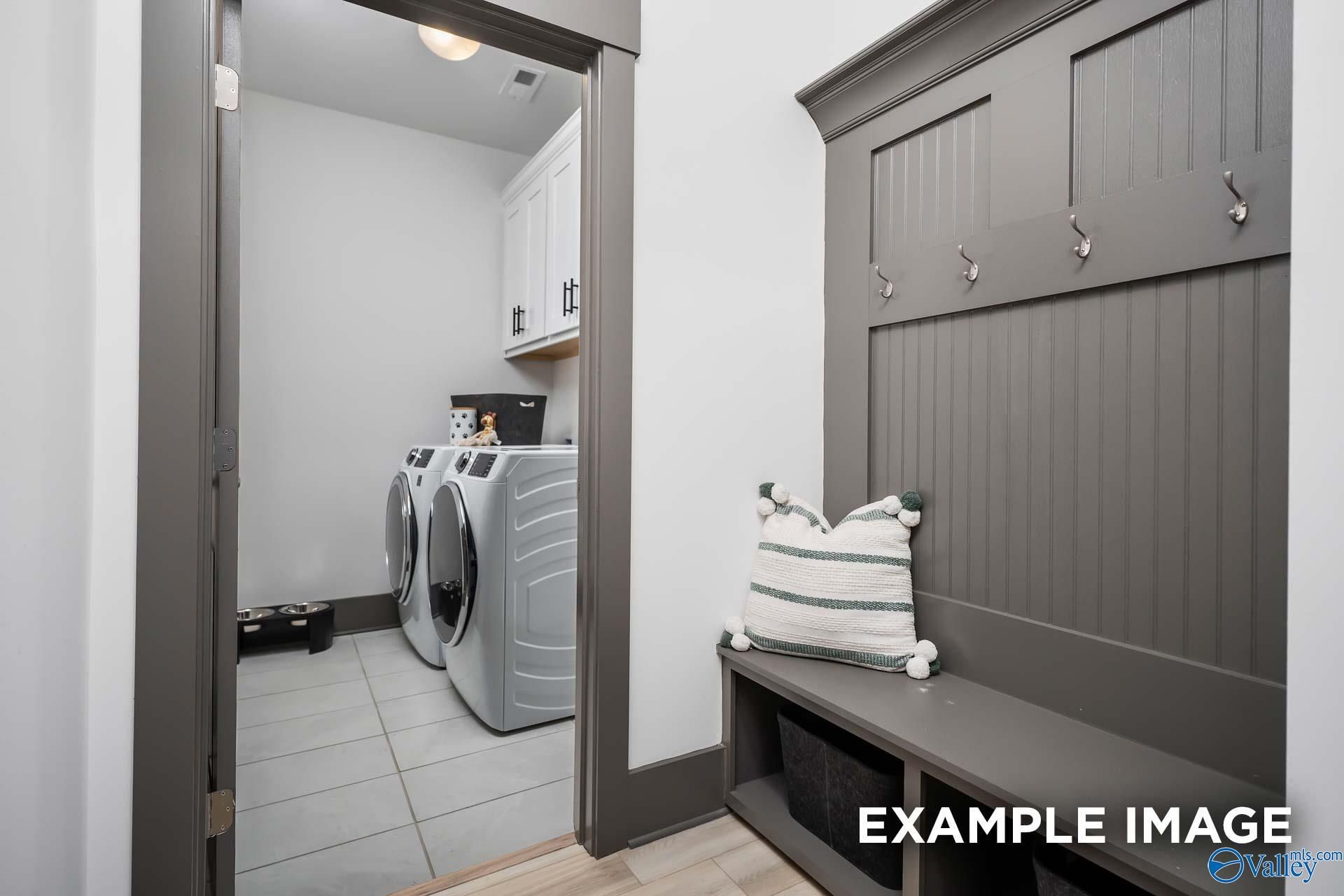 Functional laundry room with washer dryer, built-in bench, hooks and cabinets in Davidson Homes The Rockford B, Madison Alabama