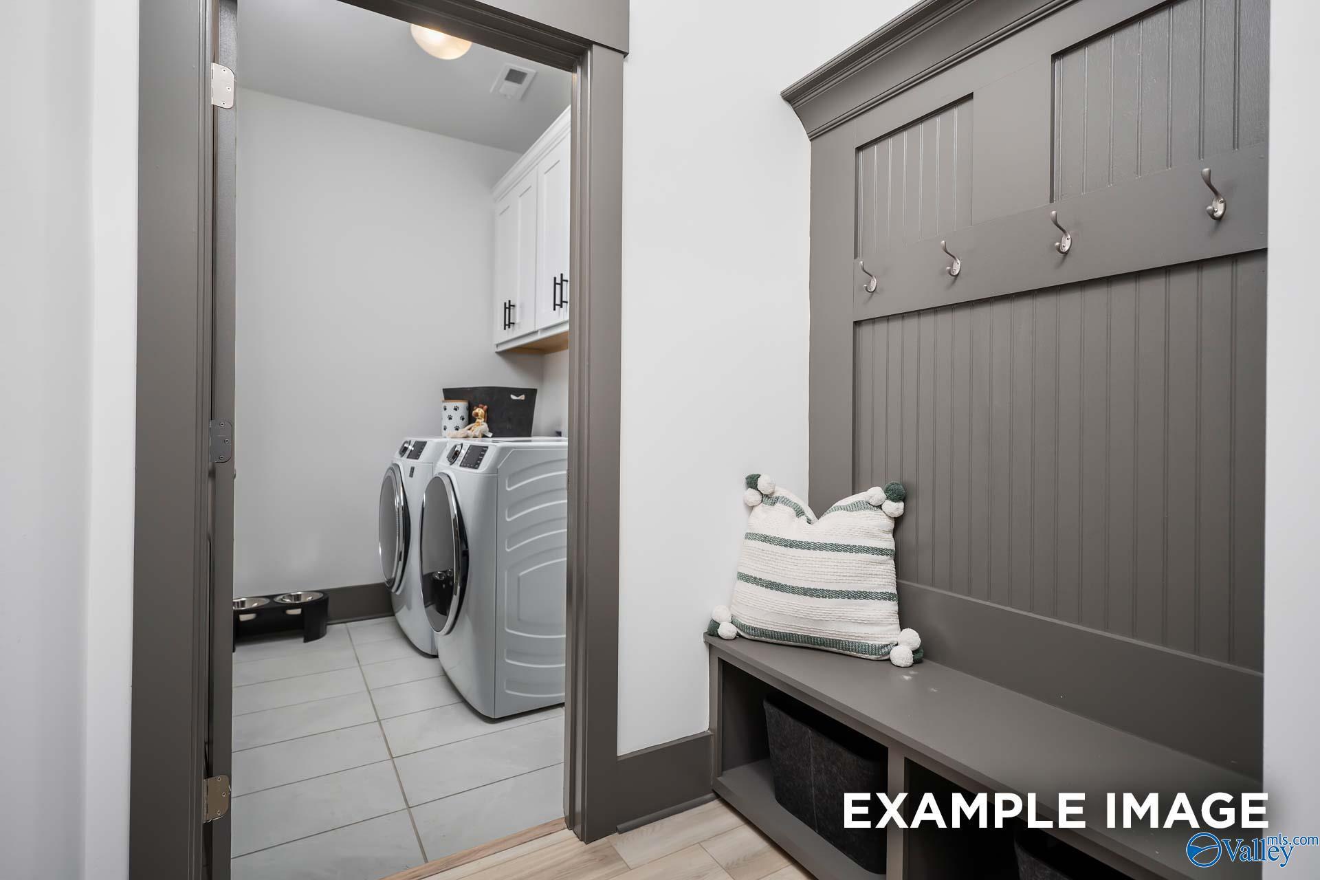 Functional laundry room with washer dryer, built-in bench, hooks and cabinets in Davidson Homes The Rockford B, Madison Alabama