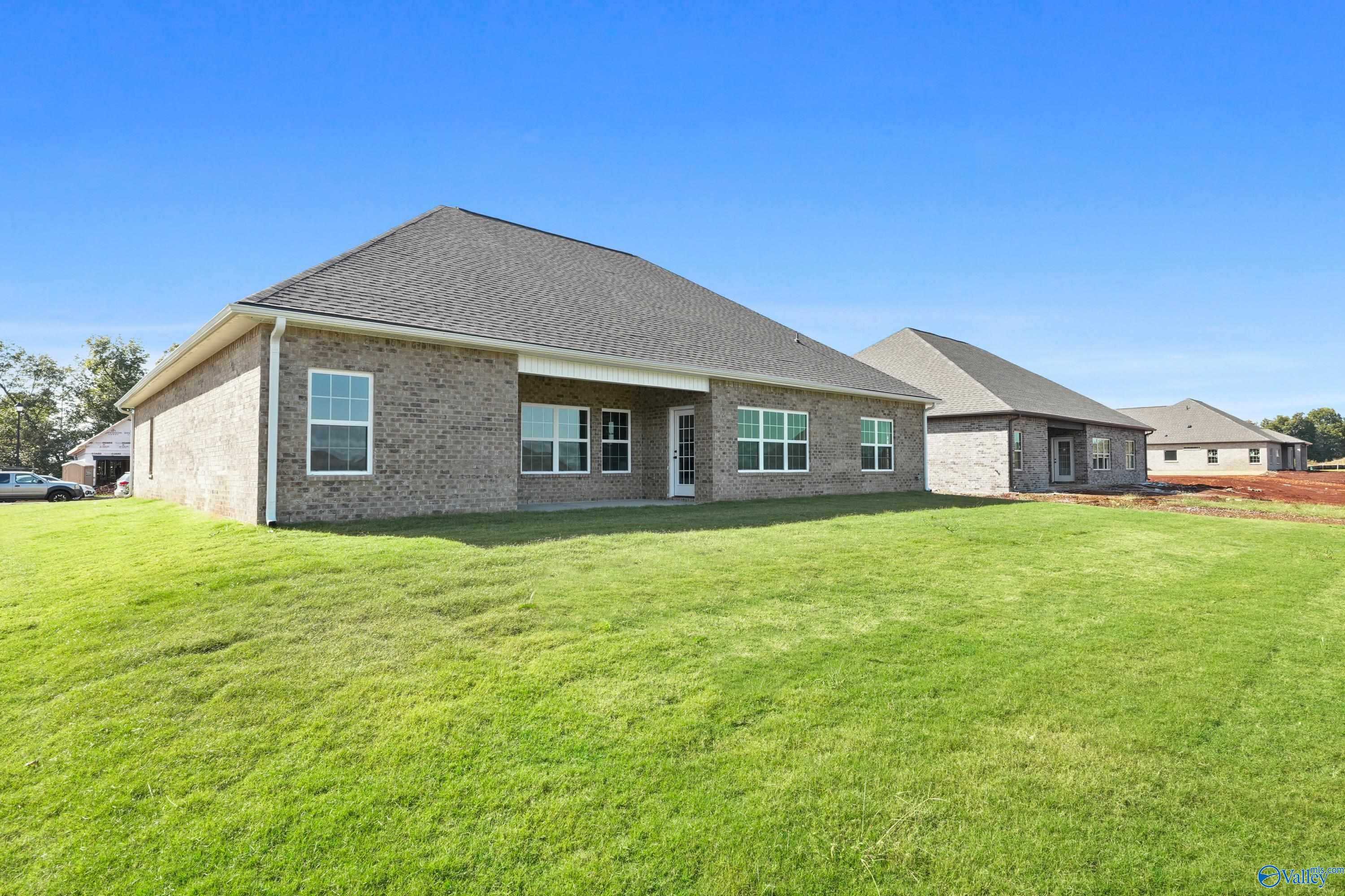 Brick 1-story The Finleigh home by Davidson Homes in Creekside, Harvest, Alabama, featuring covered patio and lush green yard