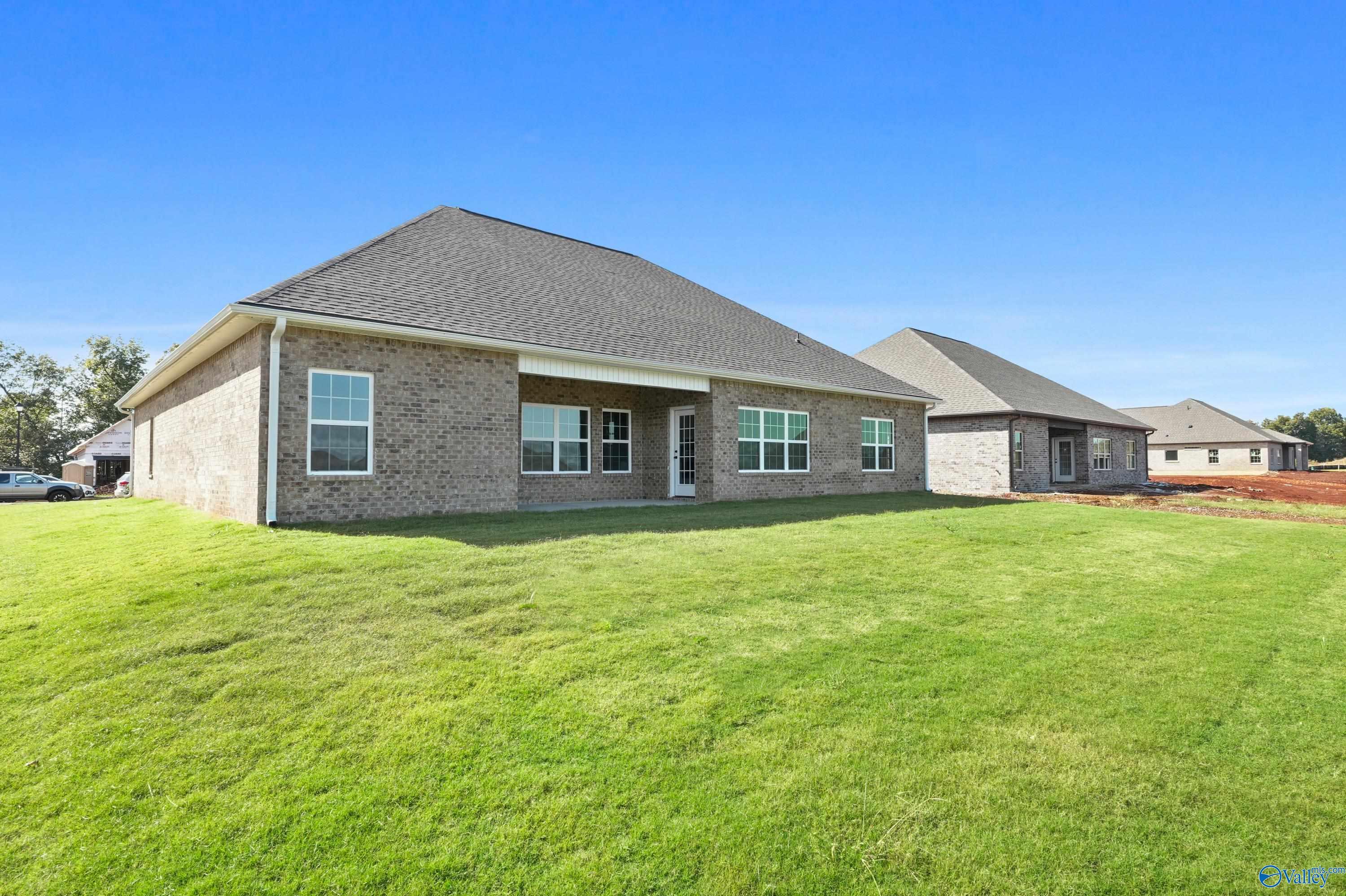 Brick 1-story The Finleigh home by Davidson Homes in Creekside, Harvest, Alabama, featuring covered patio and lush green yard