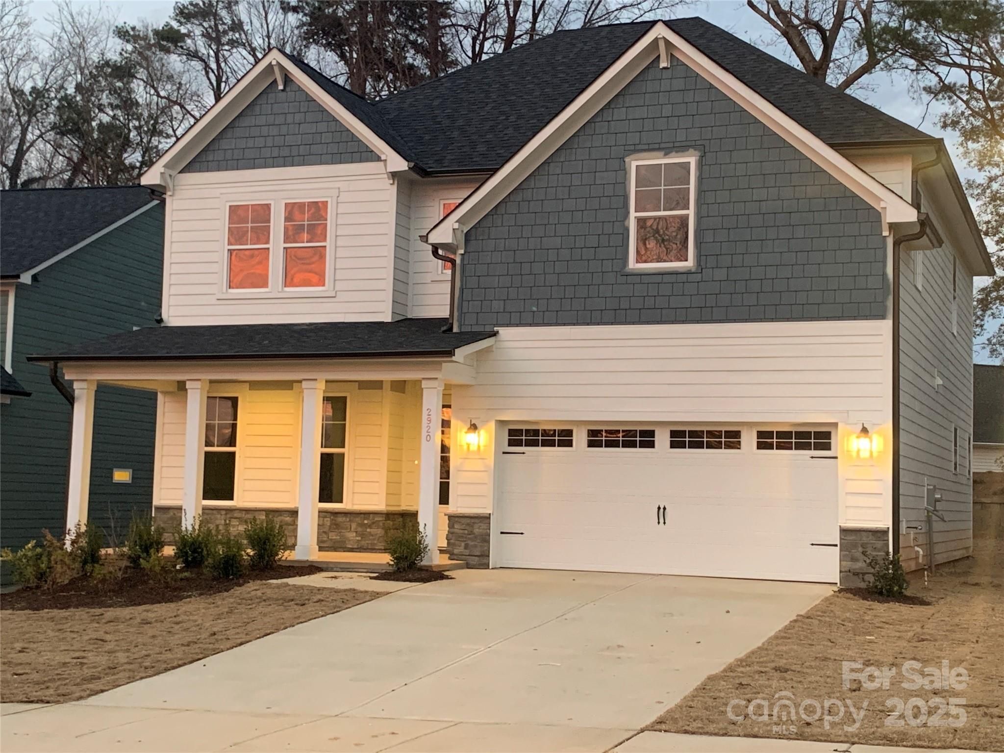 Elegant two-story Hemlock A home with gray siding, covered porch, 2-car garage, and for-sale sign in Enclave at Belmont, NC