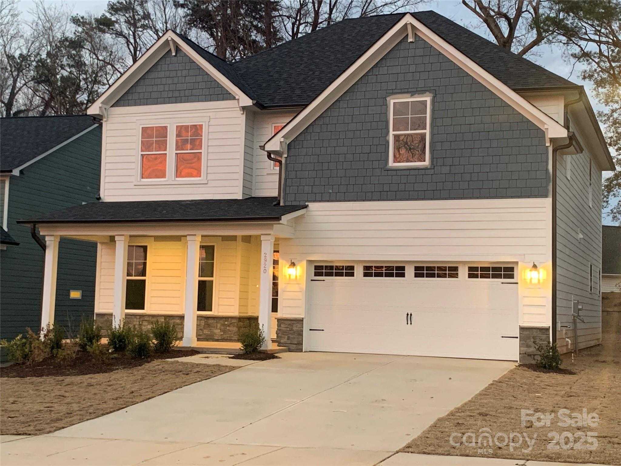 Elegant two-story Hemlock A home with gray siding, covered porch, 2-car garage, and for-sale sign in Enclave at Belmont, NC