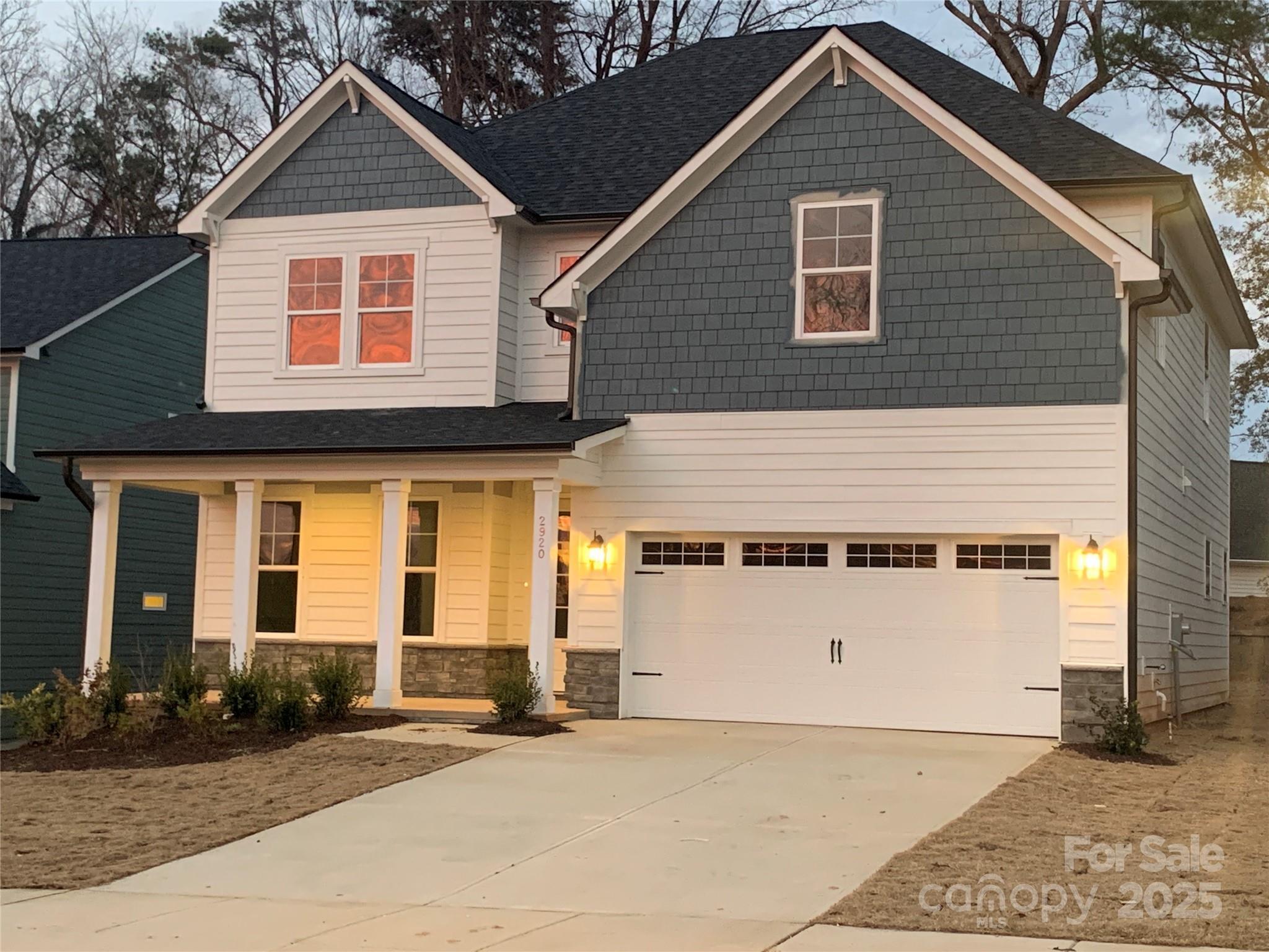 Elegant two-story Hemlock A home with gray siding, covered porch, 2-car garage, and for-sale sign in Enclave at Belmont, NC