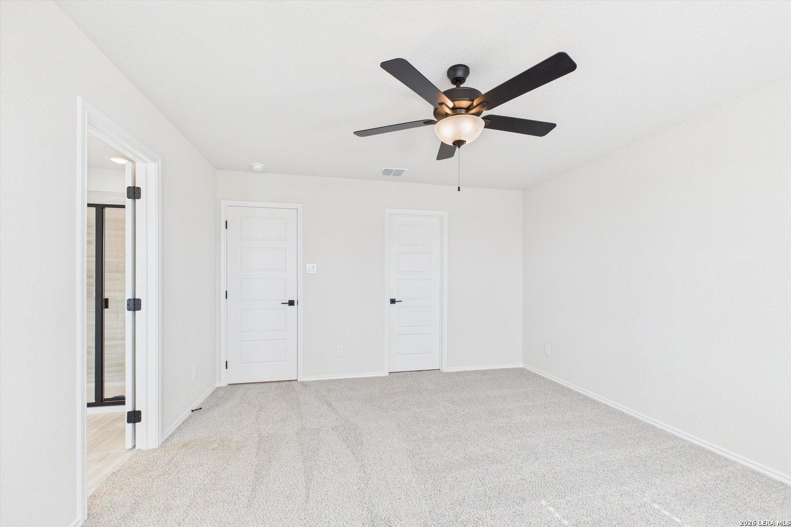 Spacious bedroom with ceiling fan, carpet floor, bathroom and closet doors in Davidson Homes The Gillian B, San Antonio, Texas