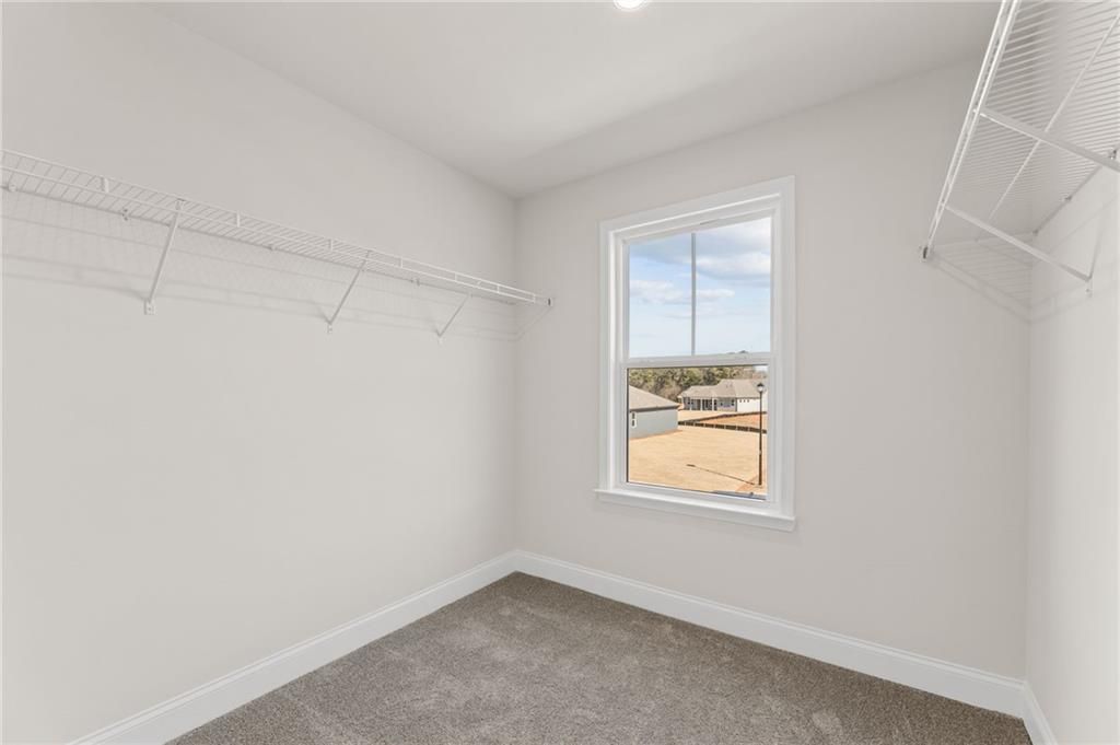 Spacious walk-in closet with wire shelving and window overlooking neighborhood in Davidson Homes The Willow B, Hoschton, GA