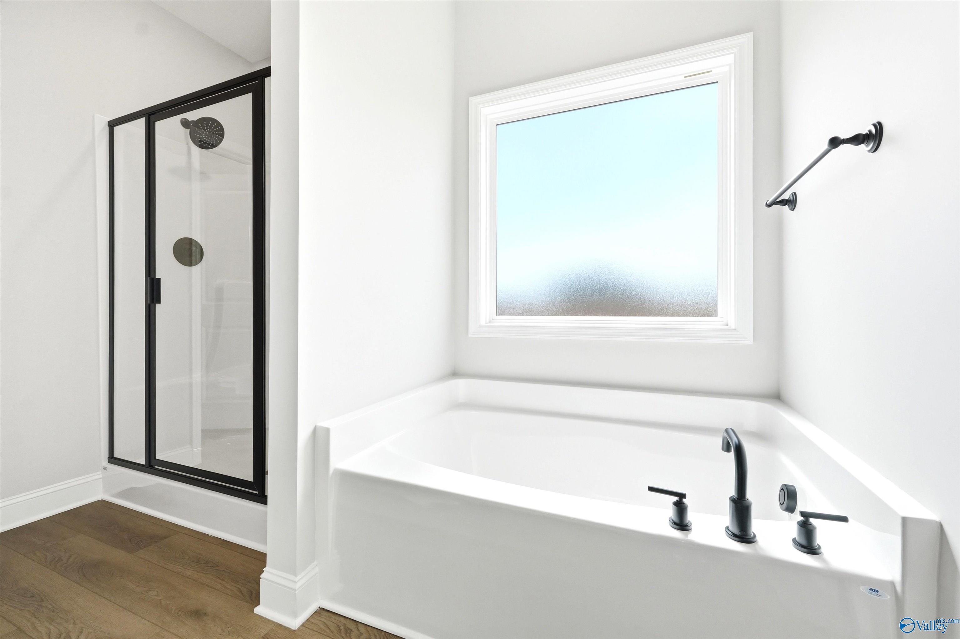 Modern master bathroom with soaking tub and glass-enclosed shower in The Daphne F floor plan at Berry Cove, New Market, AL.