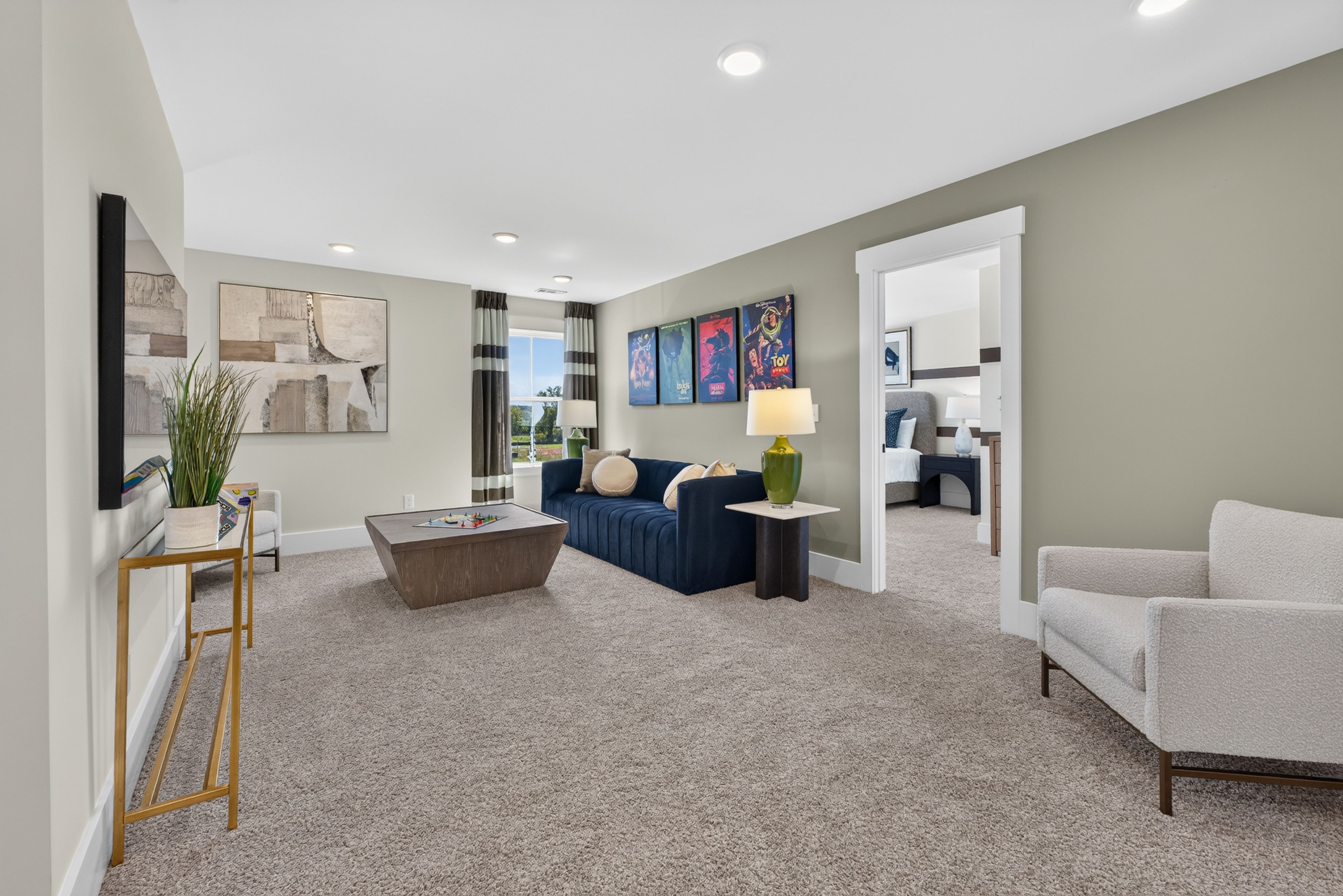 Spacious bonus room with navy sofa and plush carpet at Evergreen Mill by Davidson Homes in Madison, Alabama