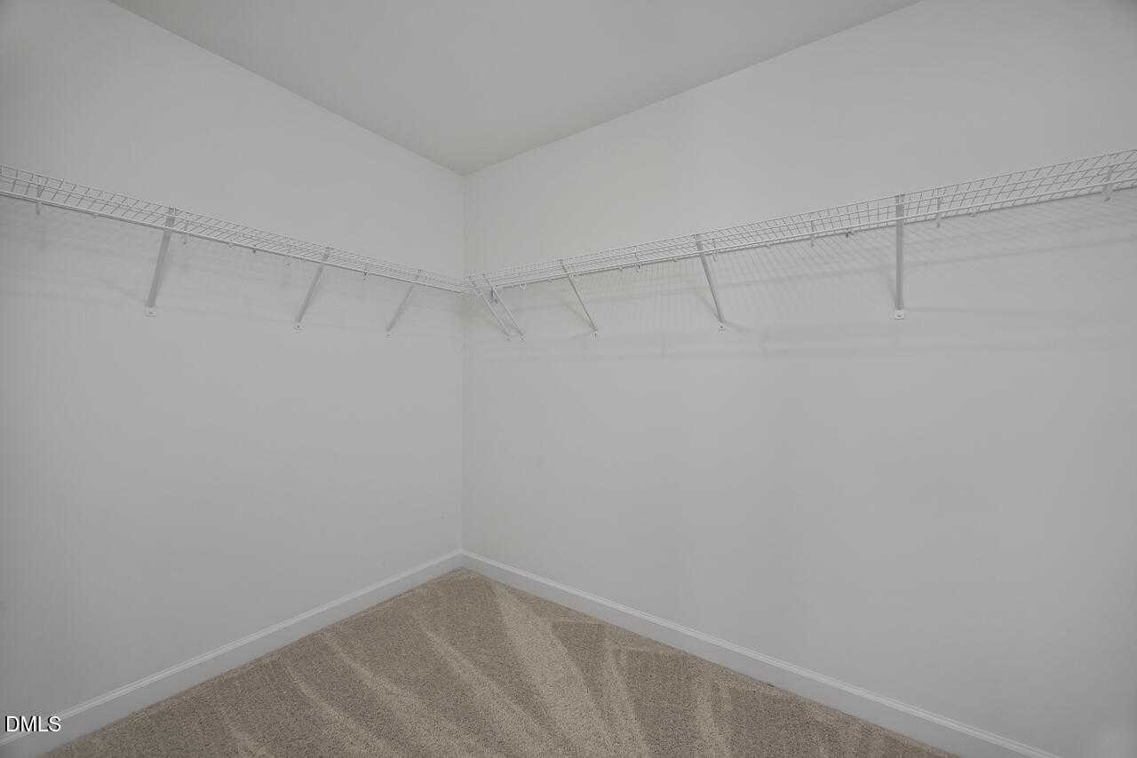 Spacious walk-in closet with wire shelving and carpeted floor in Davidson Homes The Graham, Springvale, Fuquay-Varina, NC