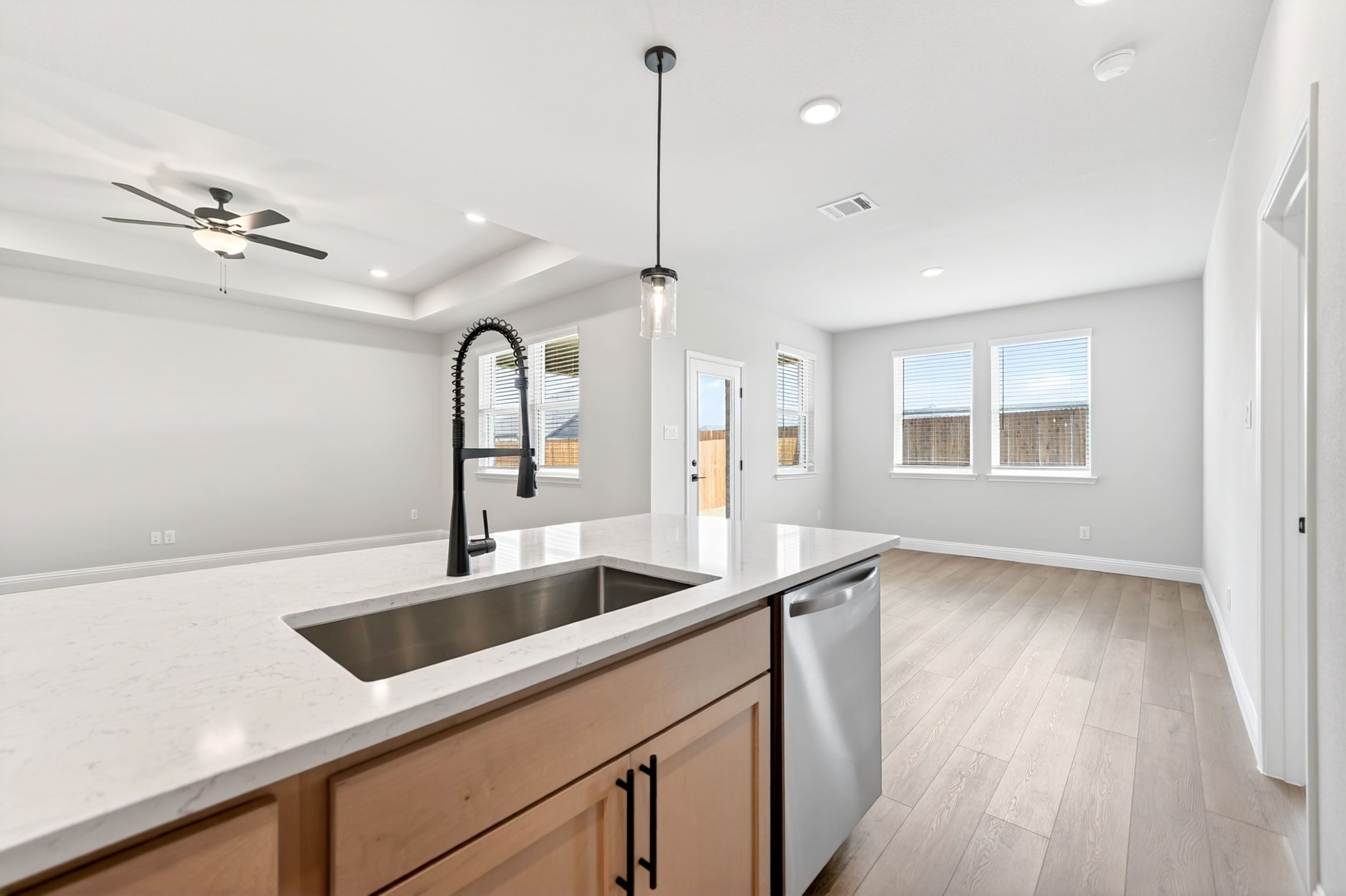 Modern kitchen island with quartz countertops and stainless steel sink in The Holly home design by Davidson Homes.