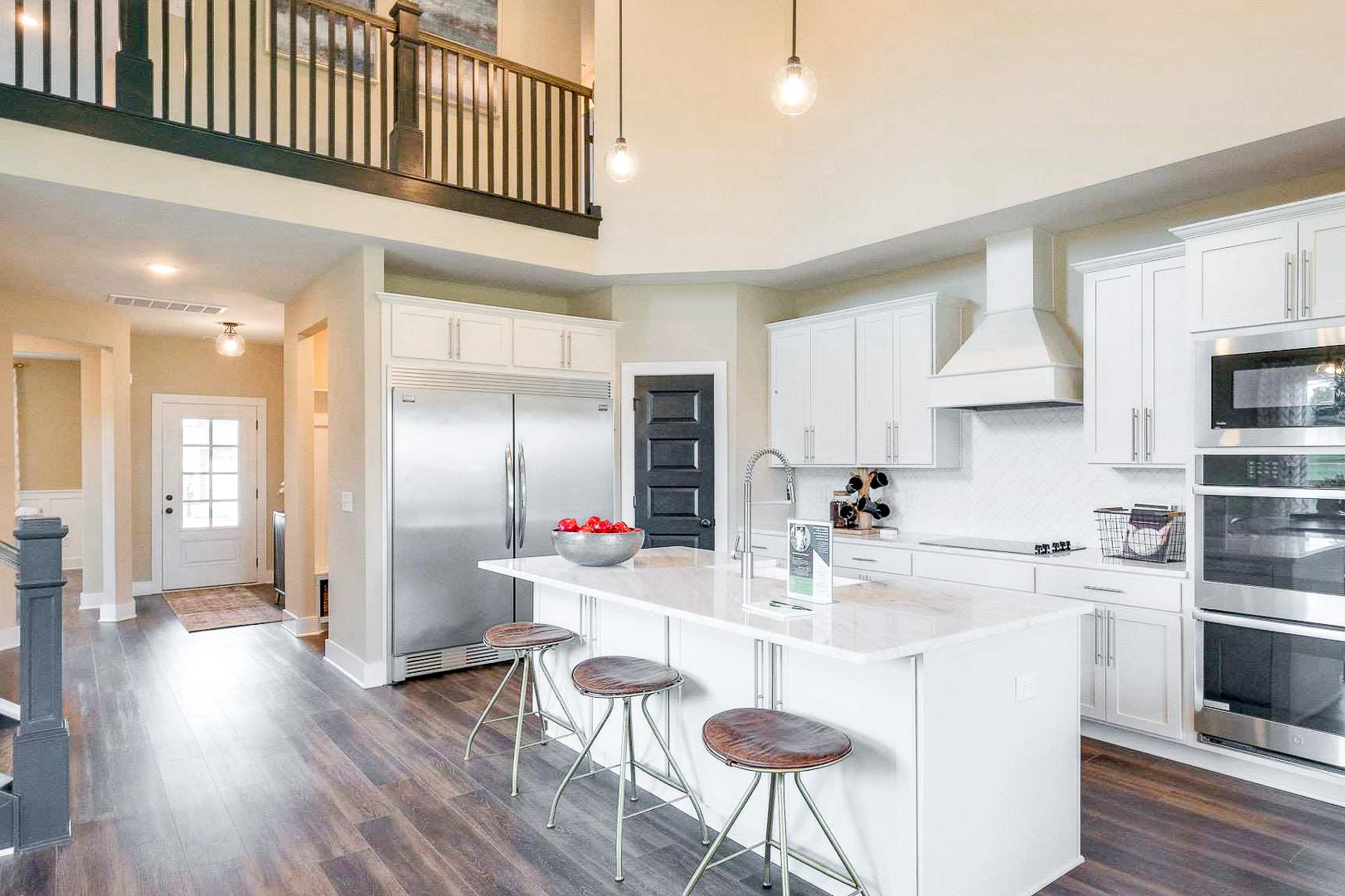 Open-concept kitchen at The Meadows in Smyrna TN with white cabinets, quartz island, stainless appliances, and hardwood floors