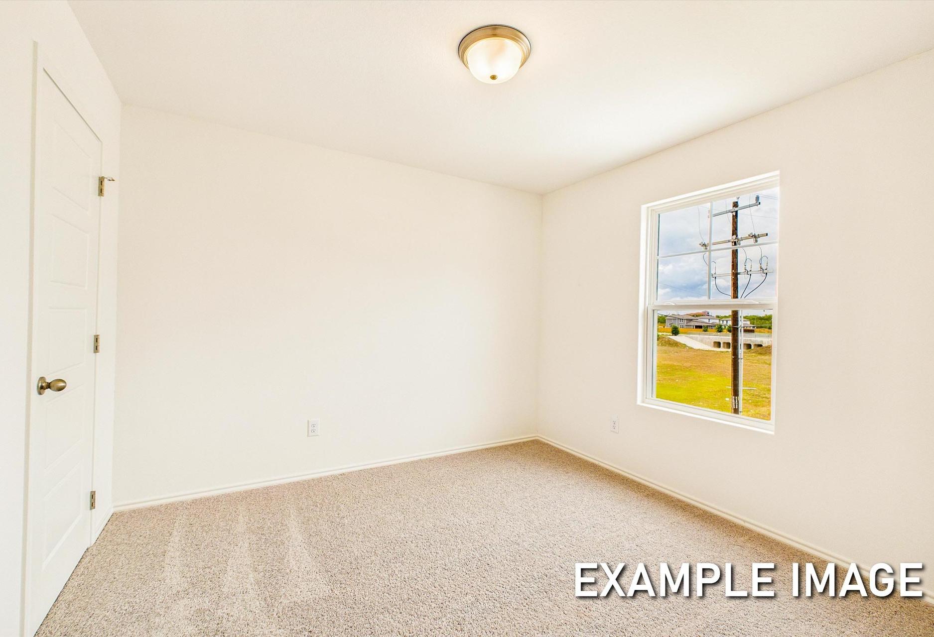 Spacious bedroom in The Trinity C with white walls, beige carpet, ceiling light, and large window overlooking green field
