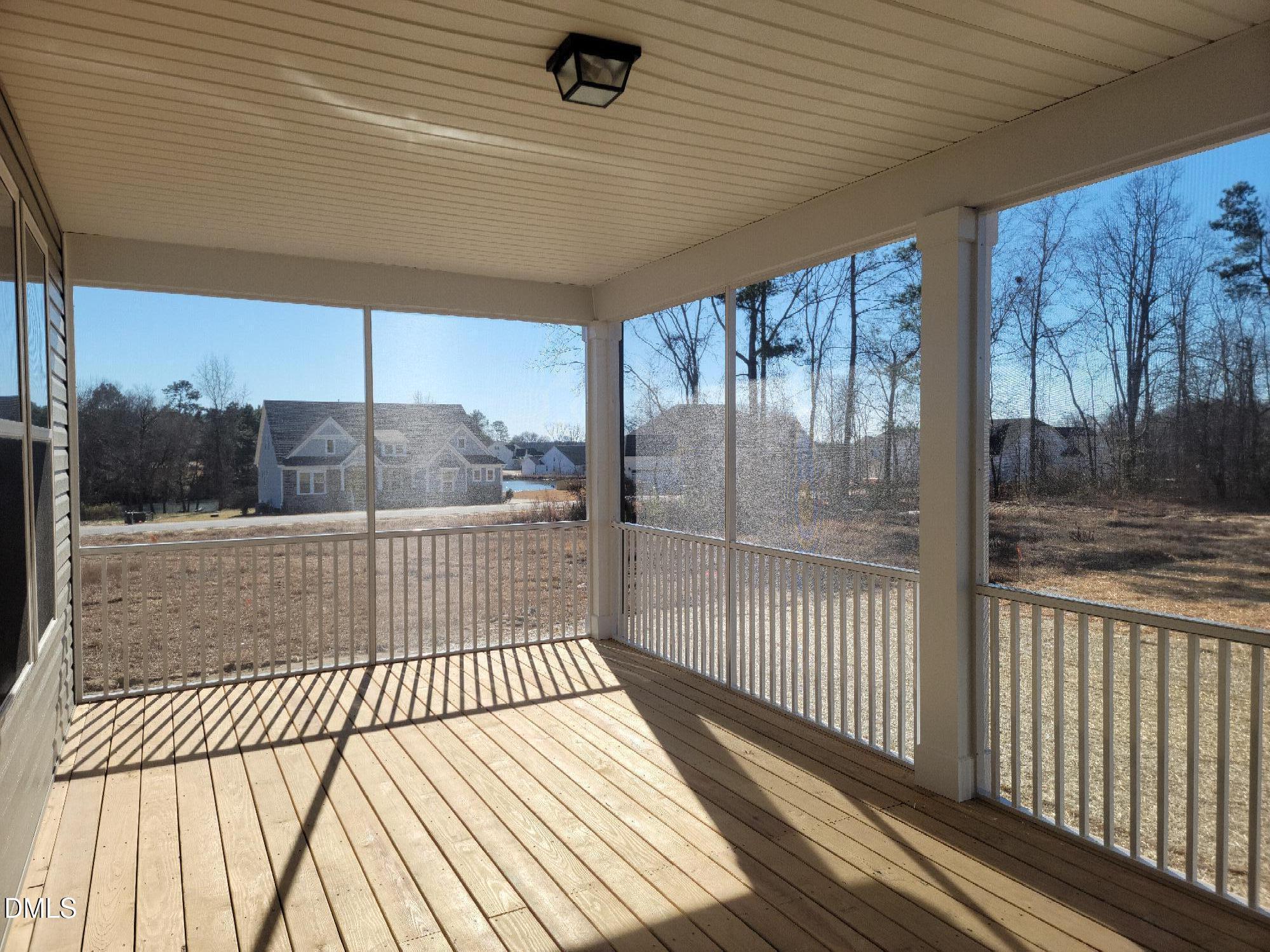 Spacious screened porch with wooden deck, vaulted ceiling, and backyard views of pines and homes in The Magnolia B, Angier, NC