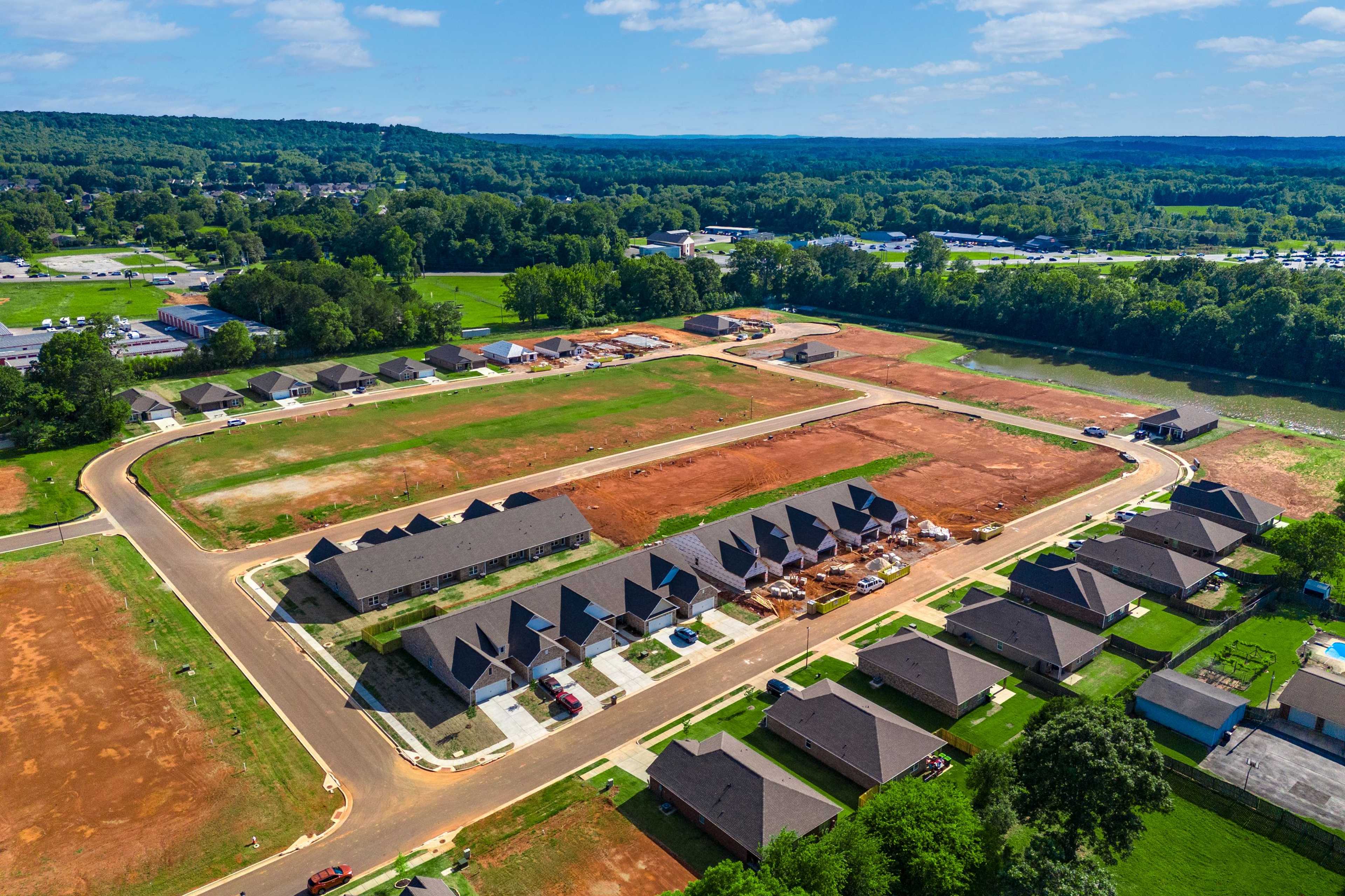 Aerial view of new homes and construction sites at The Retreat at Hollon Meadow in Decatur, Alabama with wooded hills and fields