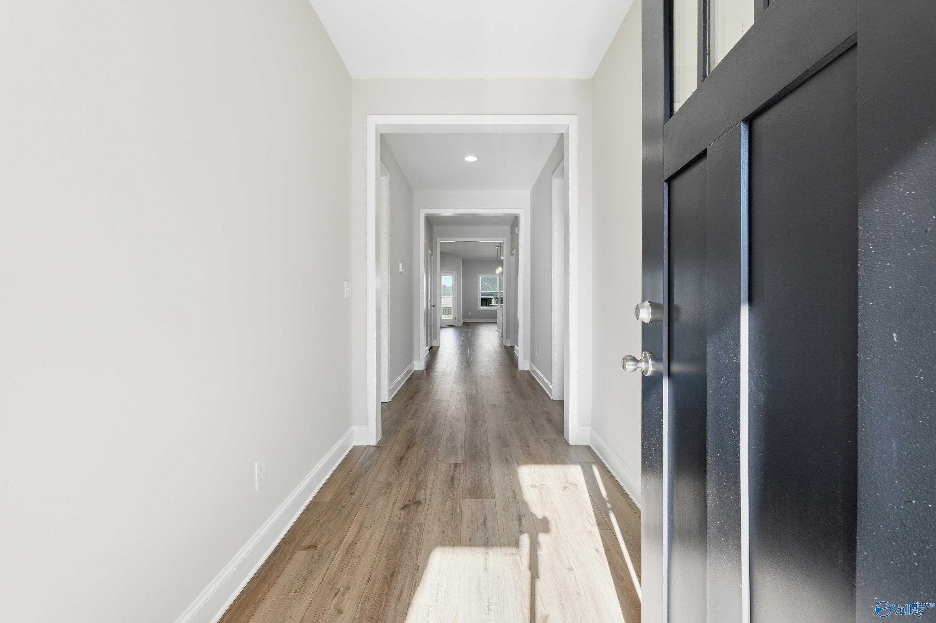 Welcoming entry foyer with hardwood floors, neutral walls, and black door in Davidson Homes The Everett, Creekside, Harvest, AL