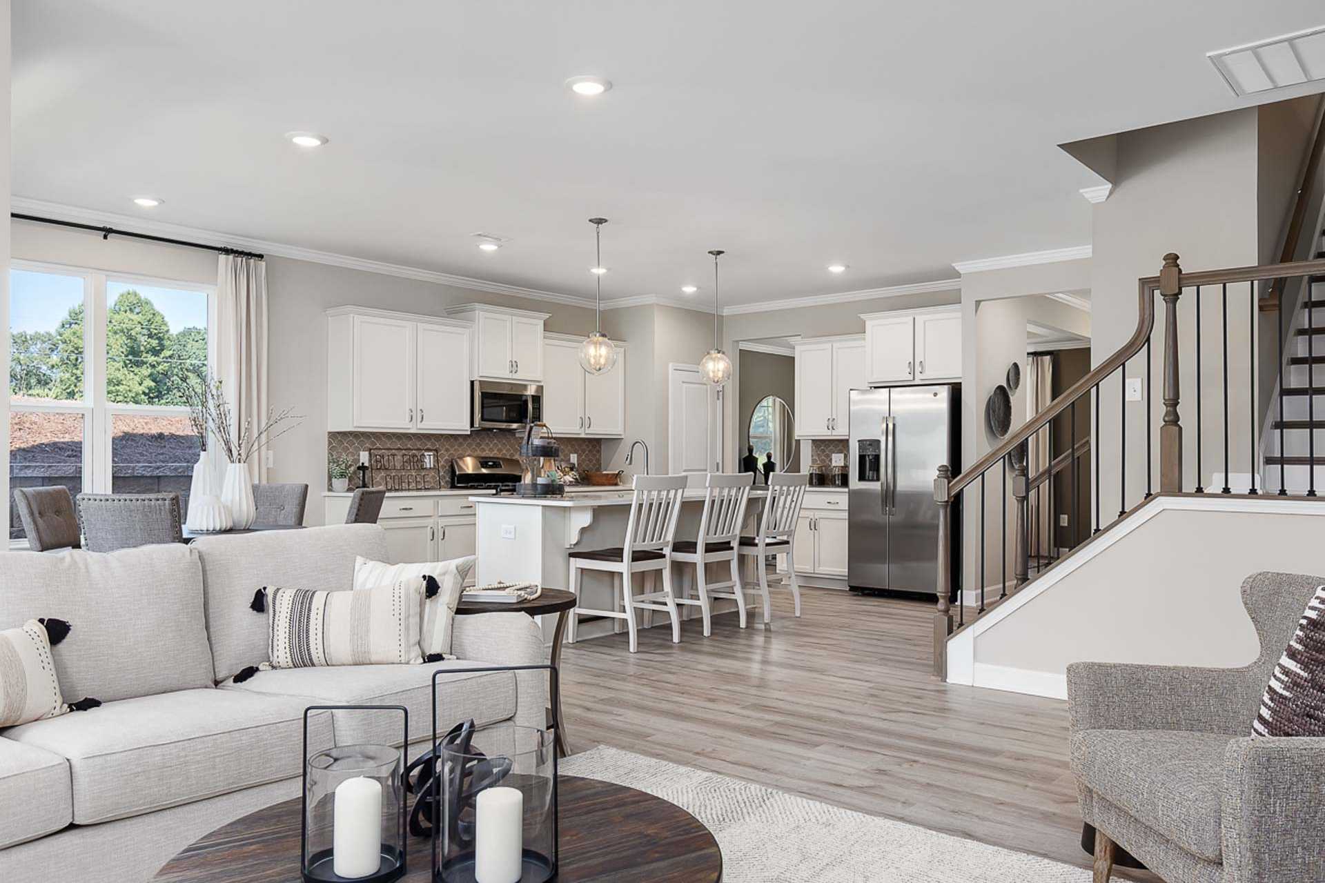 Spacious open-concept kitchen and living room at Prince Place in Fuquay-Varina NC with white cabinets, island seating, and hardwood floors