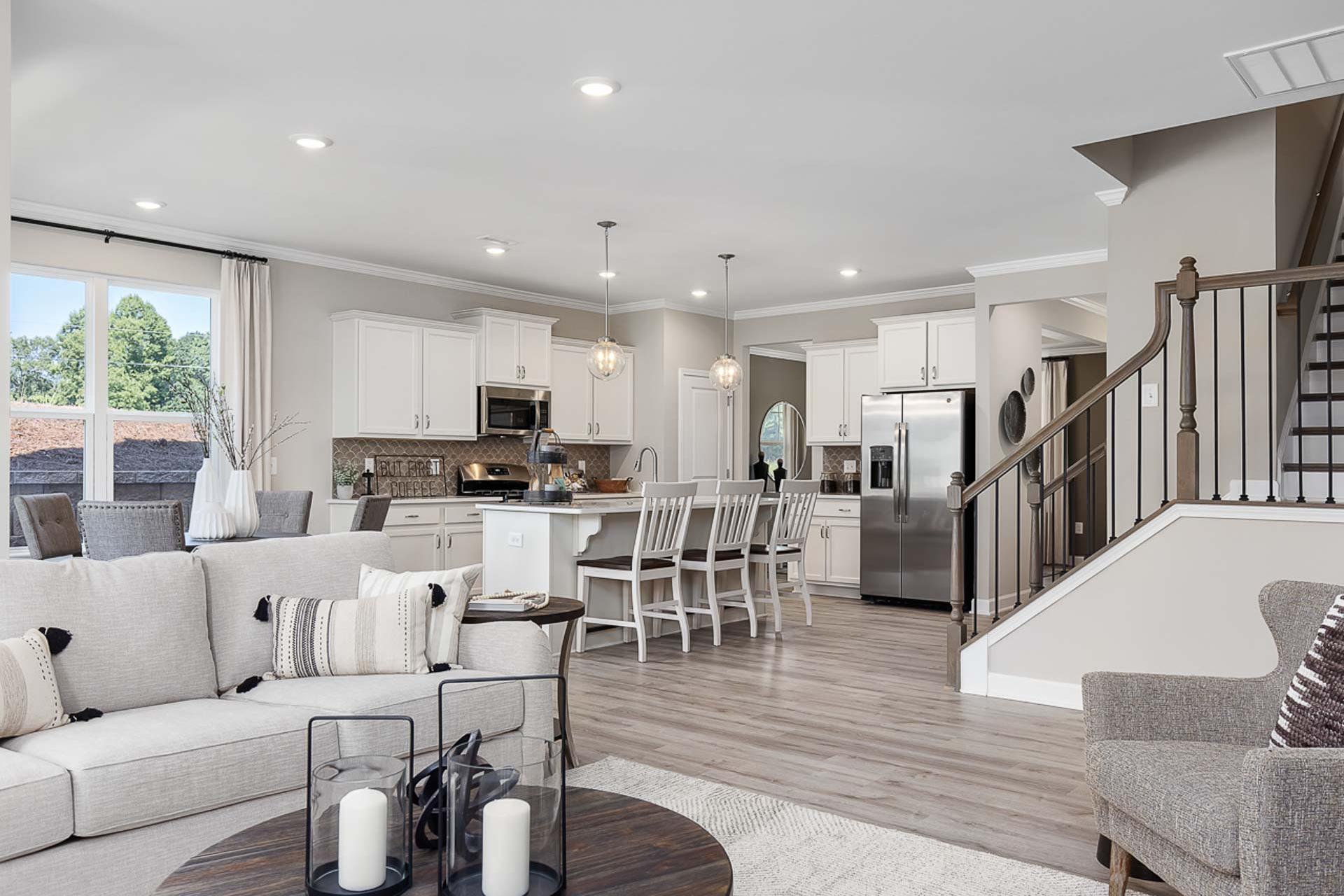 Spacious open-concept kitchen and living room at Prince Place in Fuquay-Varina NC with white cabinets, island seating, and hardwood floors