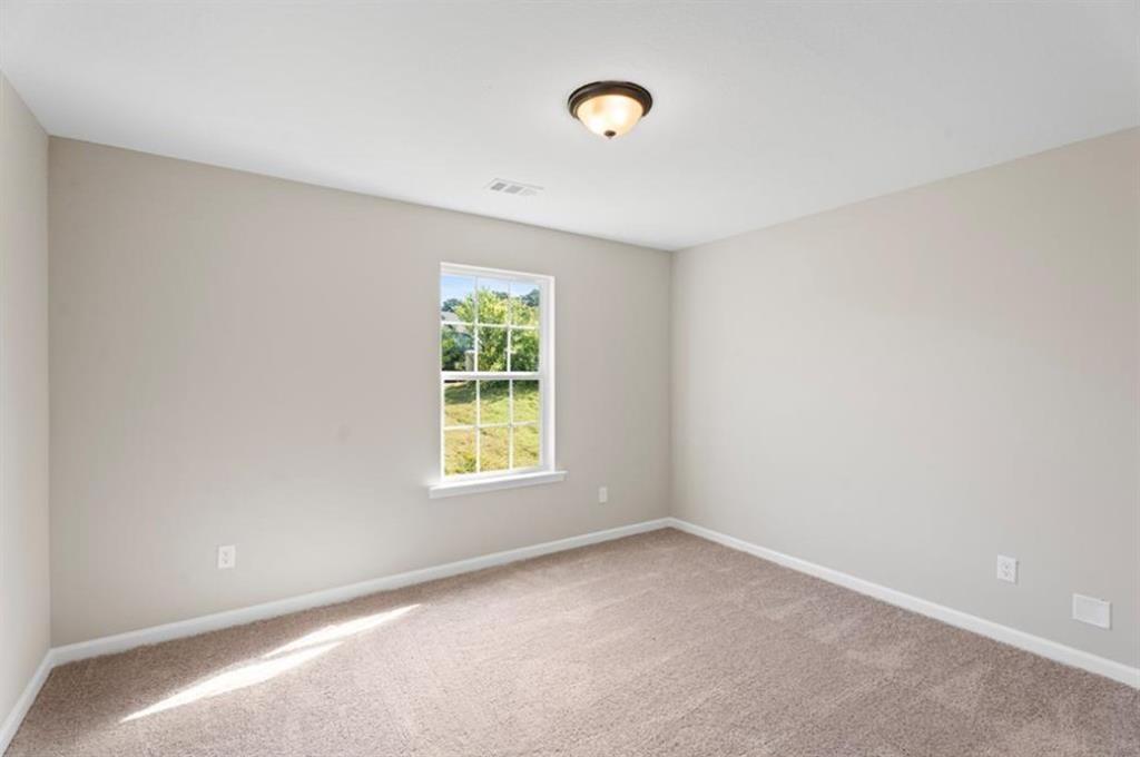 Spacious secondary bedroom with large window overlooking green yard, neutral walls, carpet floor in Davidson Homes The Washington, Phenix City