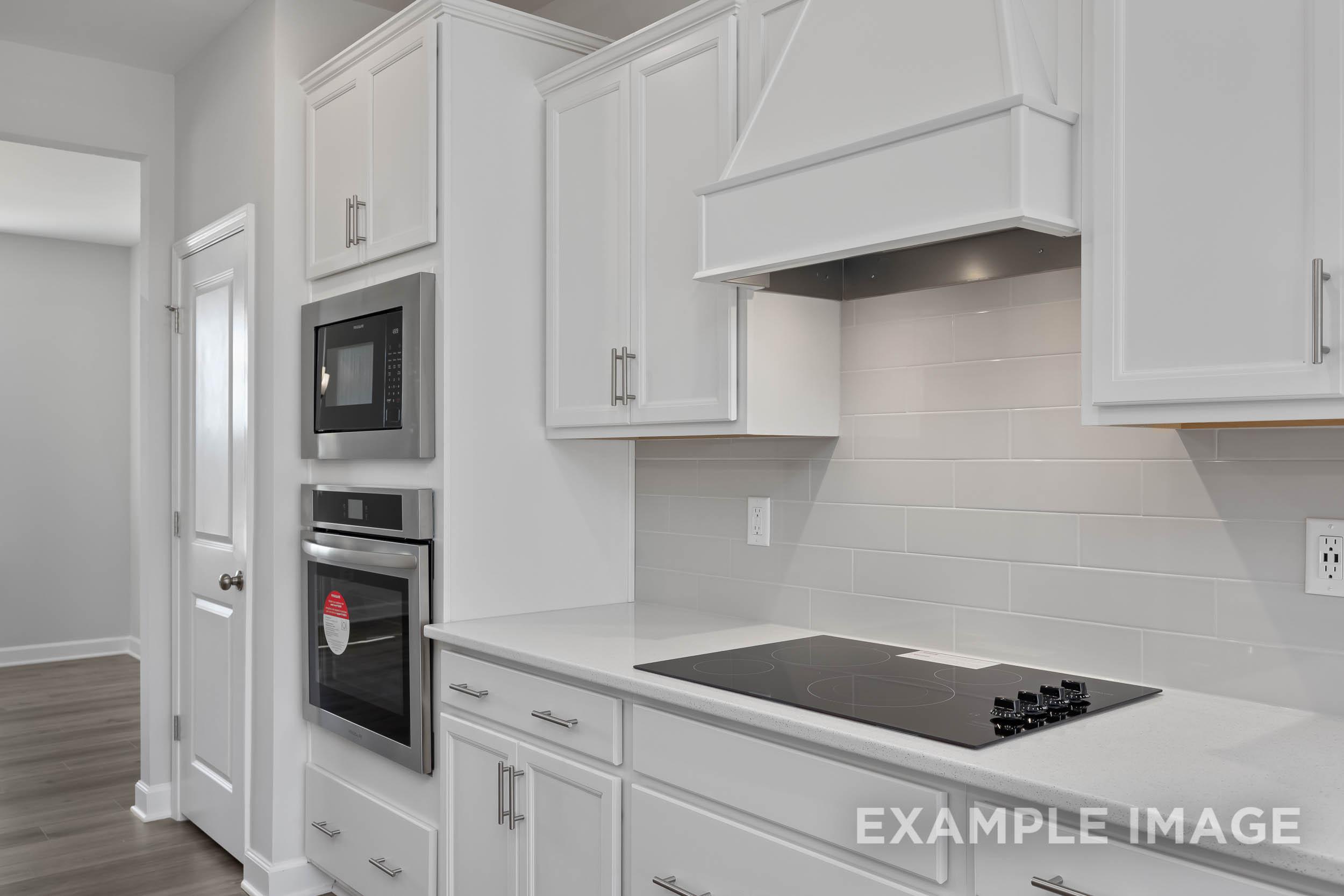 Modern white kitchen in The Ash by Davidson Homes with shaker cabinets, double wall ovens, gas cooktop, subway tile backsplash