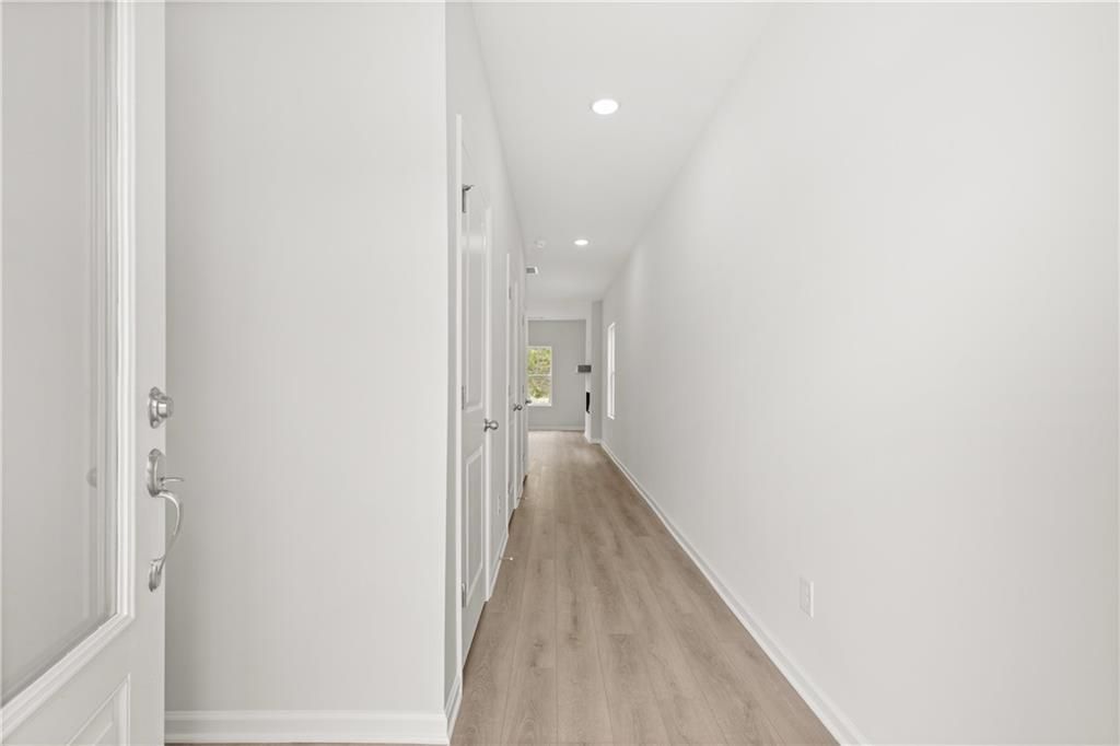 Bright, open entryway hallway with light wood-style flooring in The Burton A floor plan at The Bluffs in Canton, Georgia.