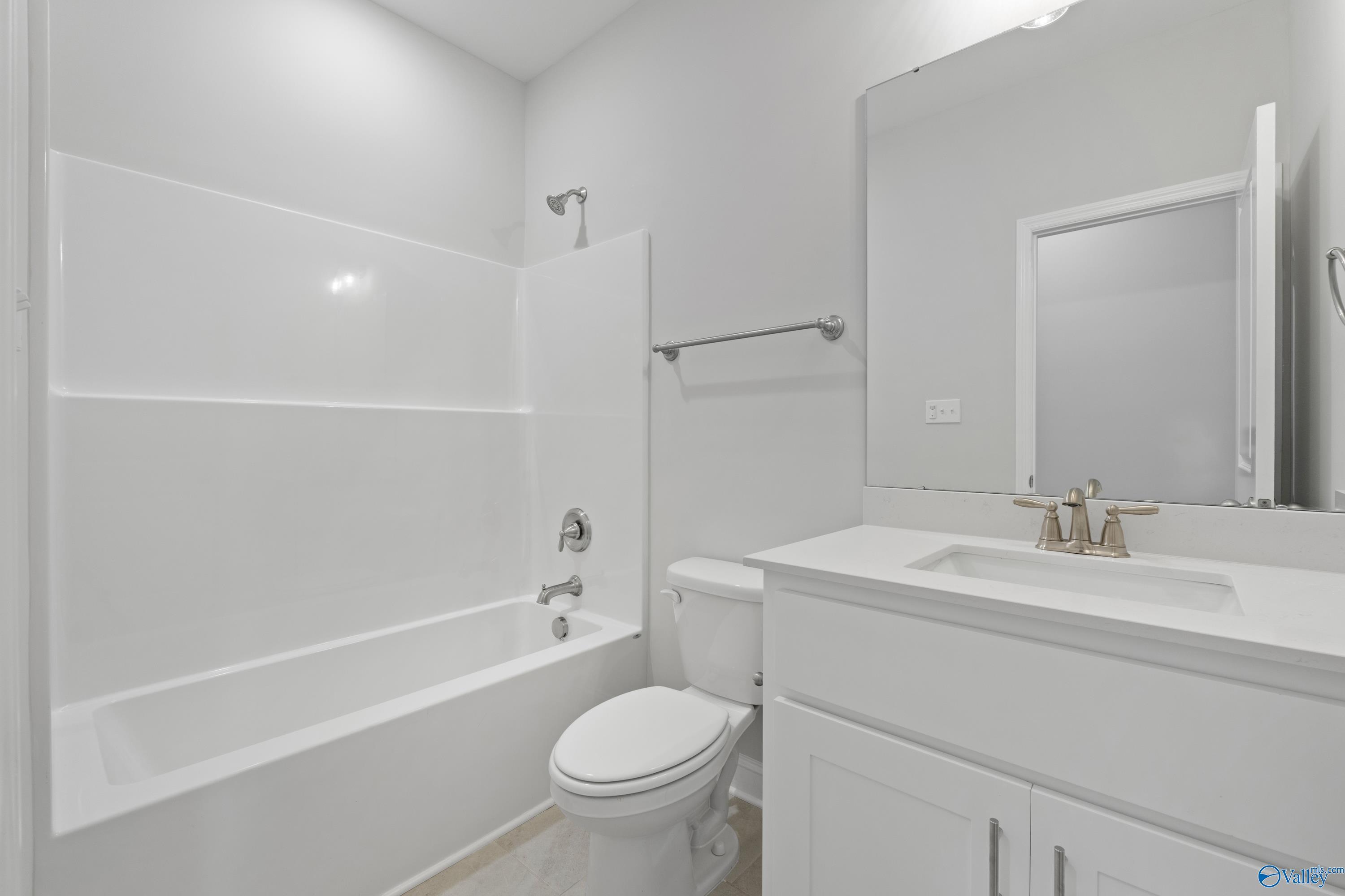 Bright white bathroom with tub-shower combo, single vanity sink, and toilet in Davidson Homes The Rockford B, Toney, Alabama