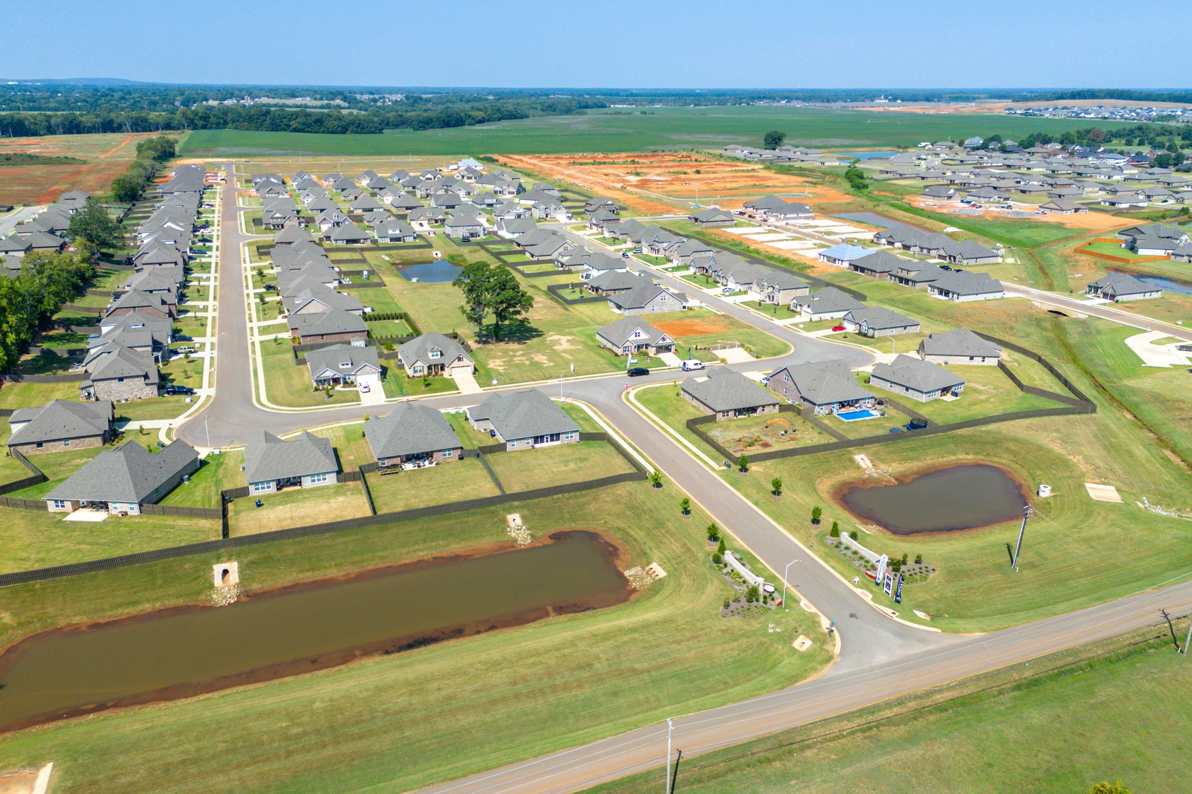 Aerial view of Pikes Ridge neighborhood in Meridianville, Alabama with new single-story homes, streets, pond, and green fields