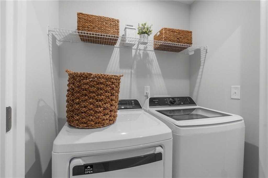 Modern laundry room featuring white washer, dryer, wicker baskets on wire shelves in Davidson Homes The Durant A, Emerson, GA