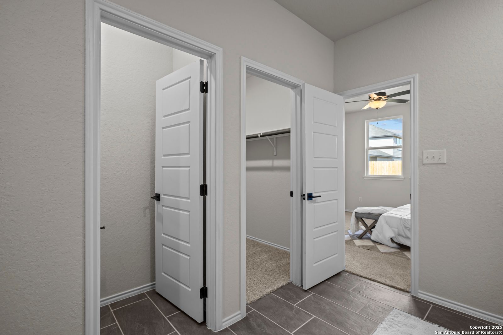 Spacious walk-in closet with shelving and bedroom entrance via white doors, ceiling fan in Davidson Homes The Douglas C, Seguin, Texas
