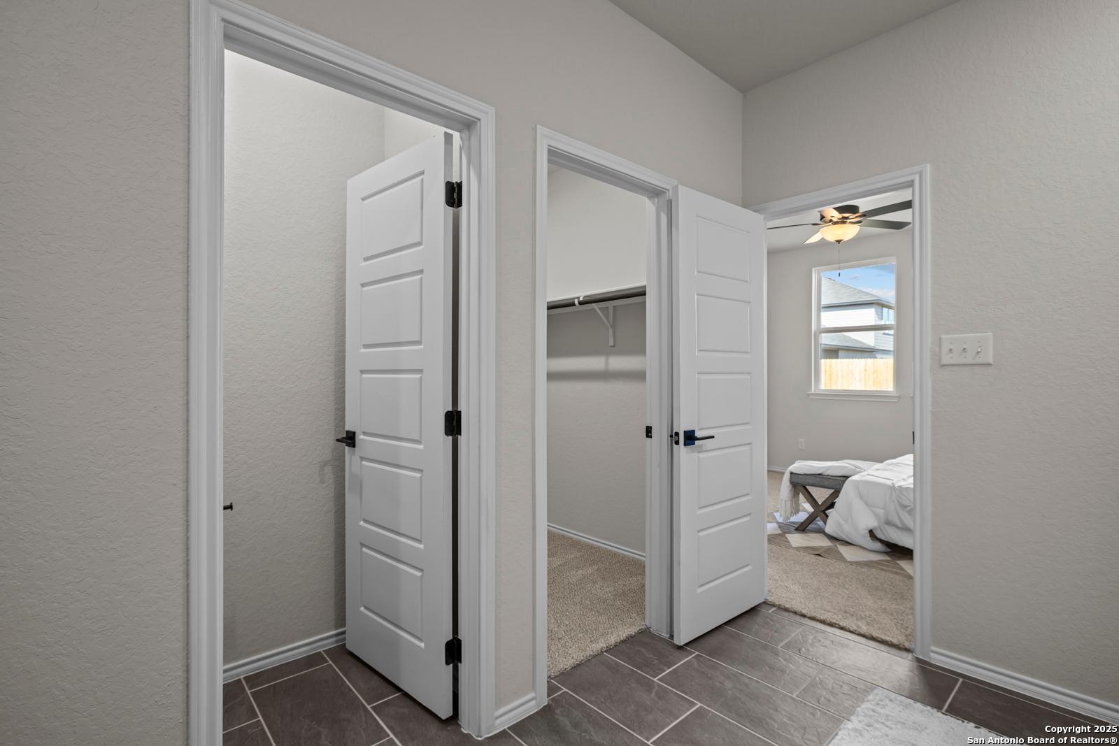 Spacious walk-in closet with shelving and bedroom entrance via white doors, ceiling fan in Davidson Homes The Douglas C, Seguin, Texas