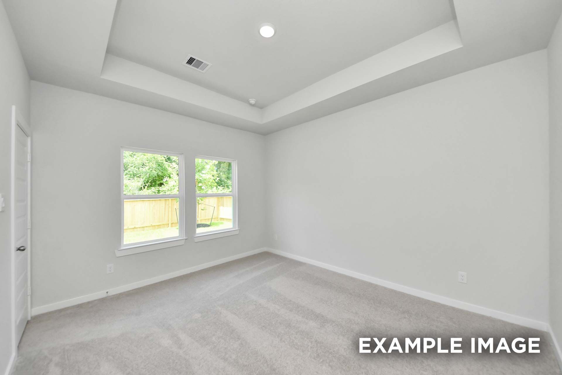 Spacious bedroom with tray ceiling and dual windows in The Blanco, a Davidson Homes new construction home in Beasley, TX.