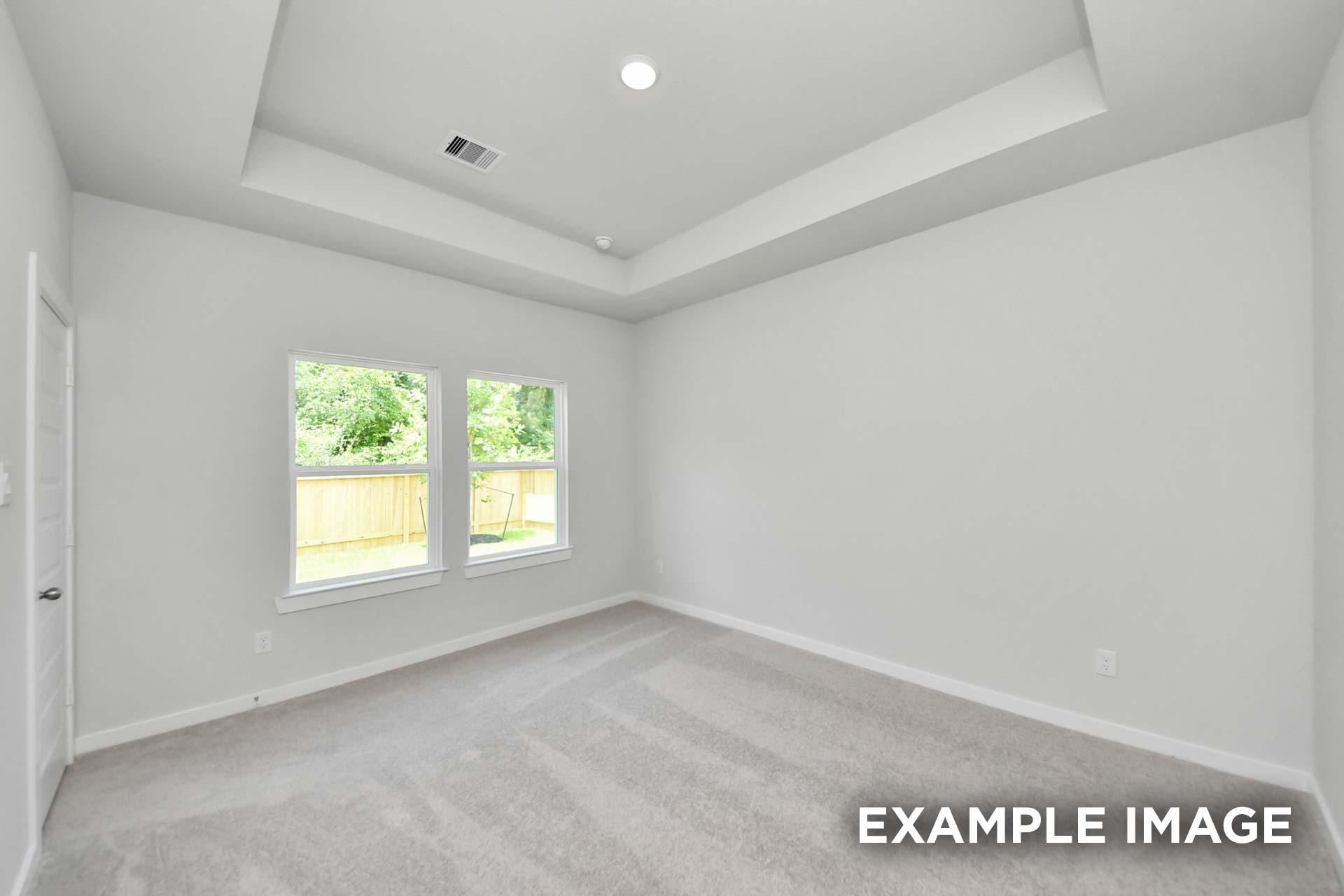 Spacious bedroom with tray ceiling and dual windows in The Blanco, a Davidson Homes new construction home in Beasley, TX.