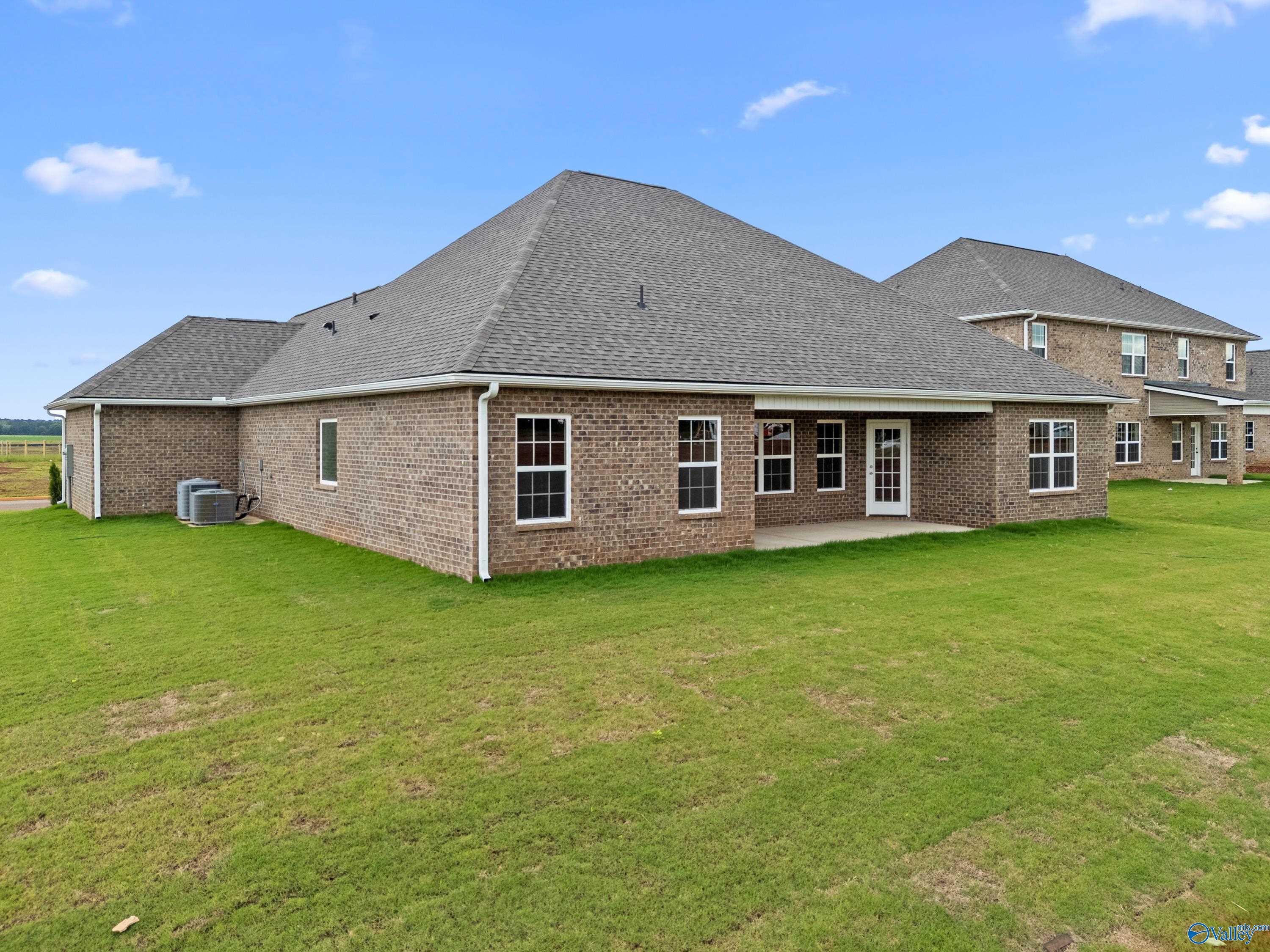 Brick single-story home rear view with covered patio, French doors, and lush green yard in Kendall Farms, Toney, Alabama Davidson Homes Rockford B