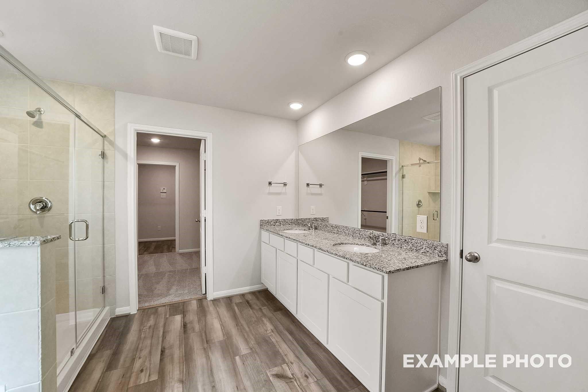 Modern master bathroom featuring double vanity with granite countertop, glass shower enclosure in Davidson Homes The Tierra B, Beasley, Texas