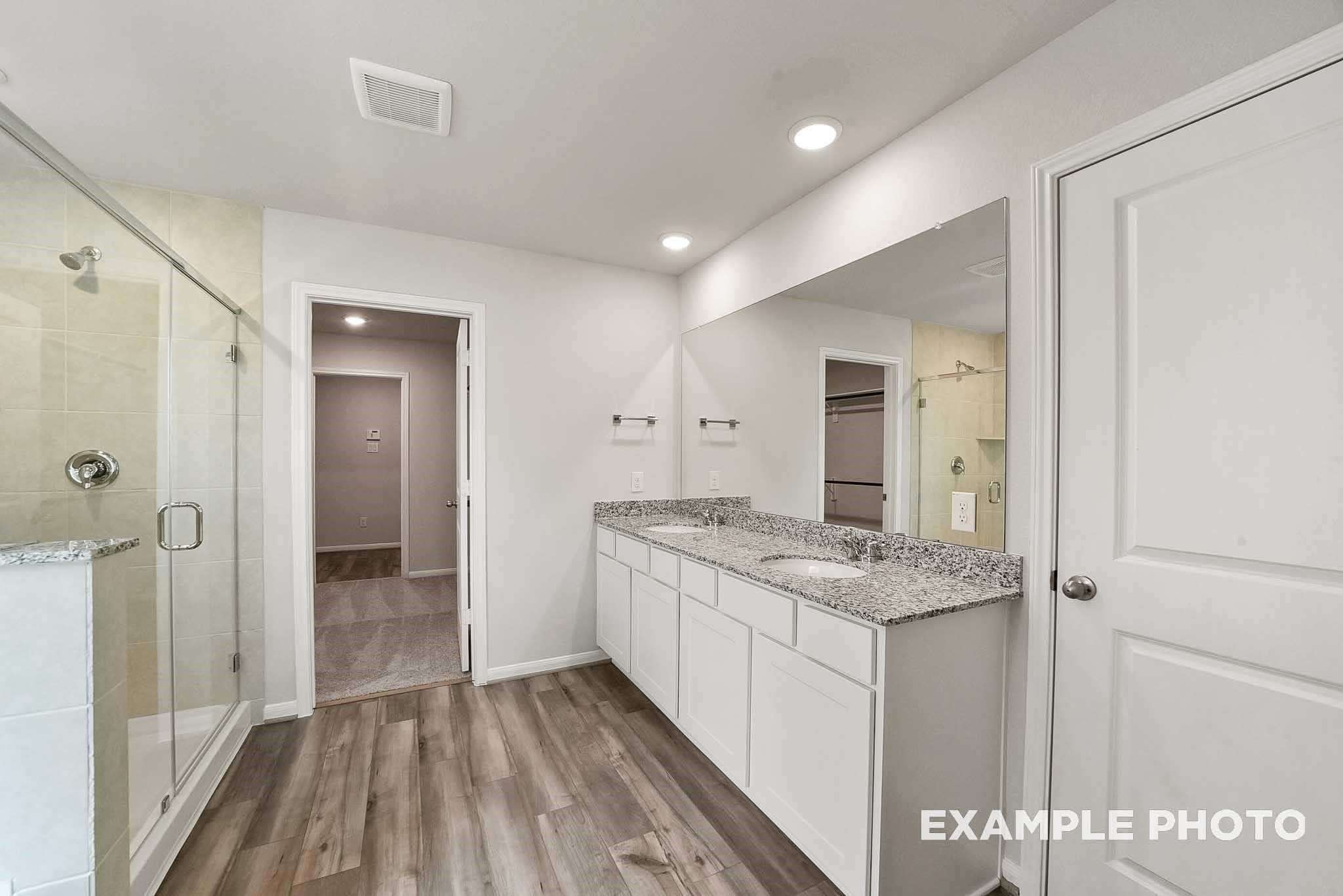Modern master bathroom featuring double vanity with granite countertop, glass shower enclosure in Davidson Homes The Tierra B, Beasley, Texas